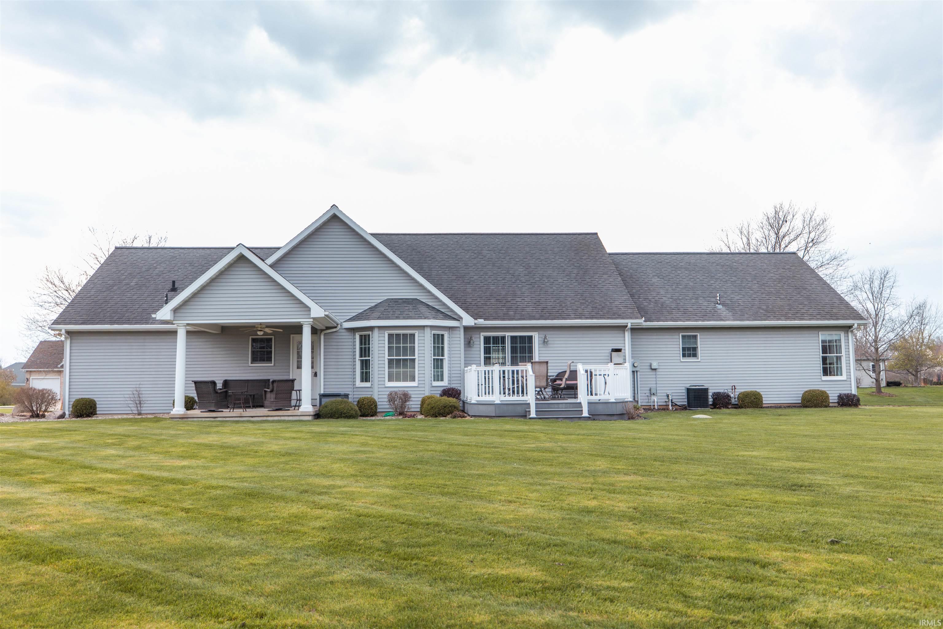 Back of house with a deck, a lawn, and roof with shingles