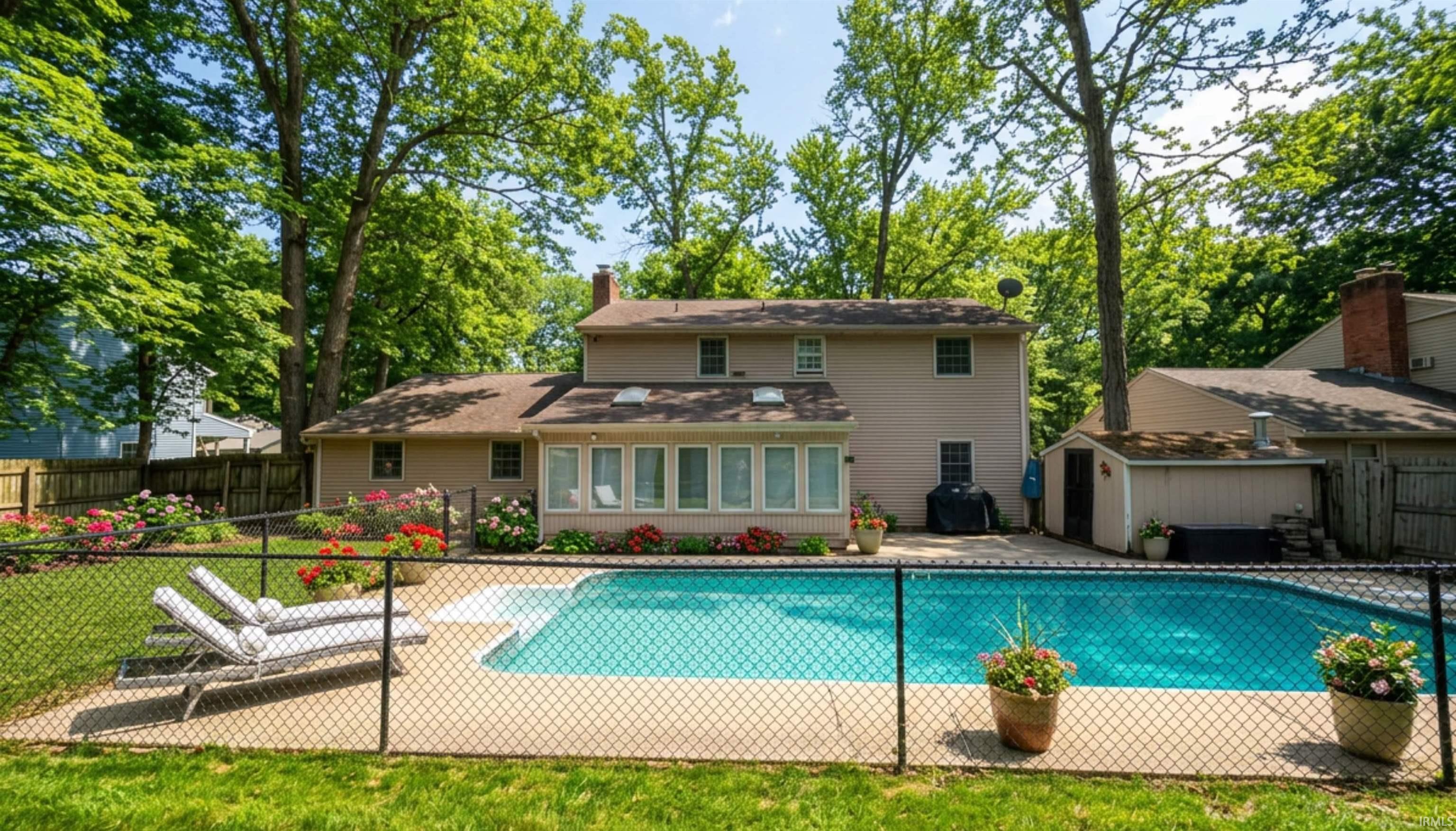 Back of property with a patio, a fenced backyard, a sunroom, a chimney, and a storage shed. (AI Generated staging)