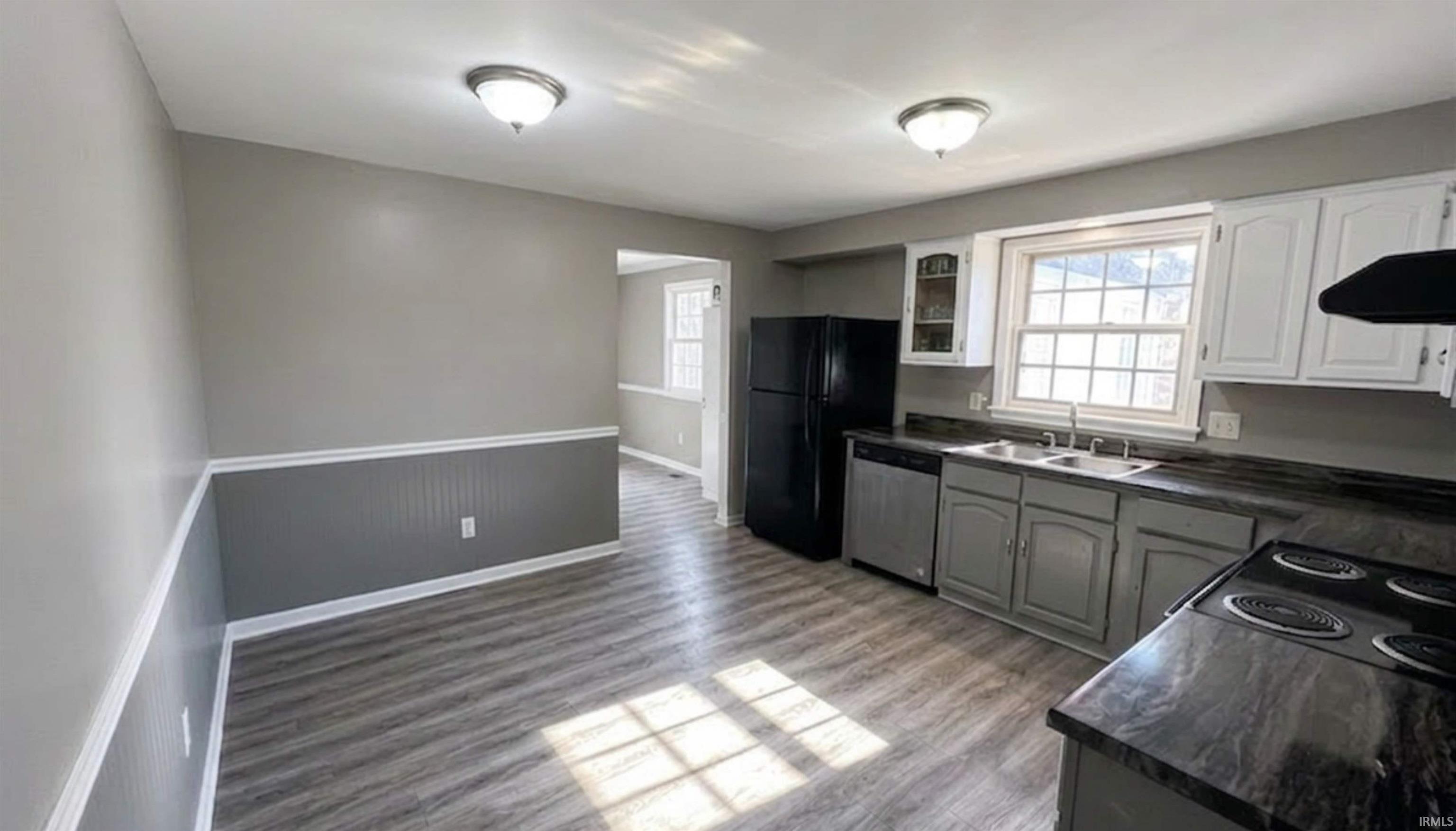 Kitchen featuring stone countertops, wood floors, stainless steel dishwasher, black appliances. (AI Generated staging)