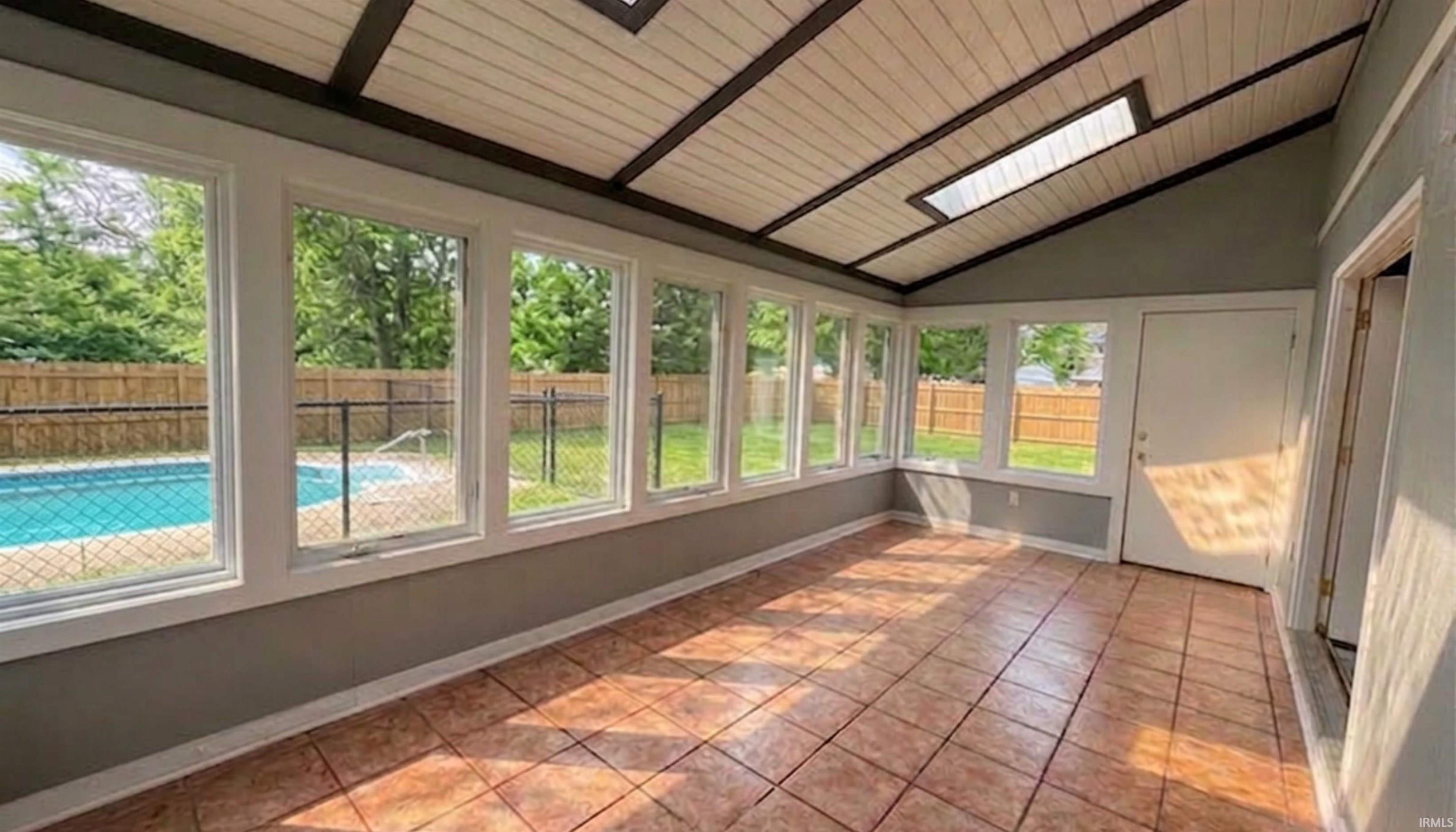 Florida sunroom featuring ceramic tile flooring, healthy amount of natural light, and a vaulted wooden ceiling, with a view of the backyard and in-ground pool. (AI Generated staging)