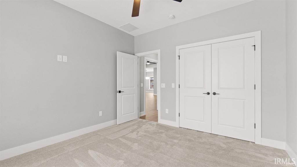 Unfurnished bedroom with light carpet, a ceiling fan, and a closet
