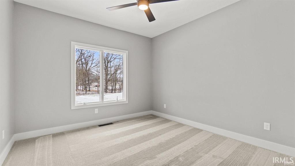 Empty room featuring a ceiling fan and light carpet