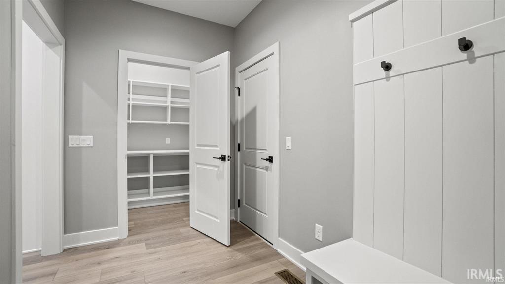 Mudroom with light wood-style flooring and baseboards
