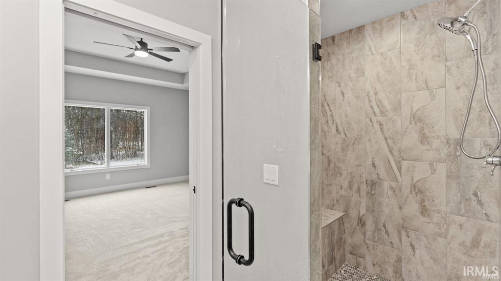 Full bathroom with a stall shower, a ceiling fan, and carpet