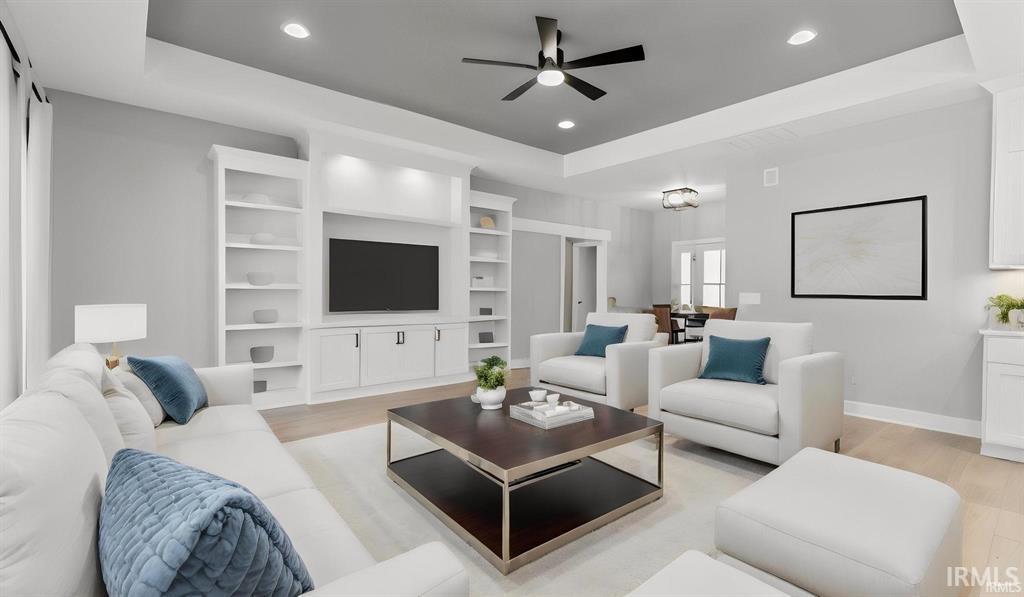 Living room with a tray ceiling, light wood-style flooring, a ceiling fan, and recessed lighting