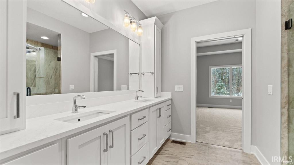 Full bath featuring double vanity and a marble finish shower