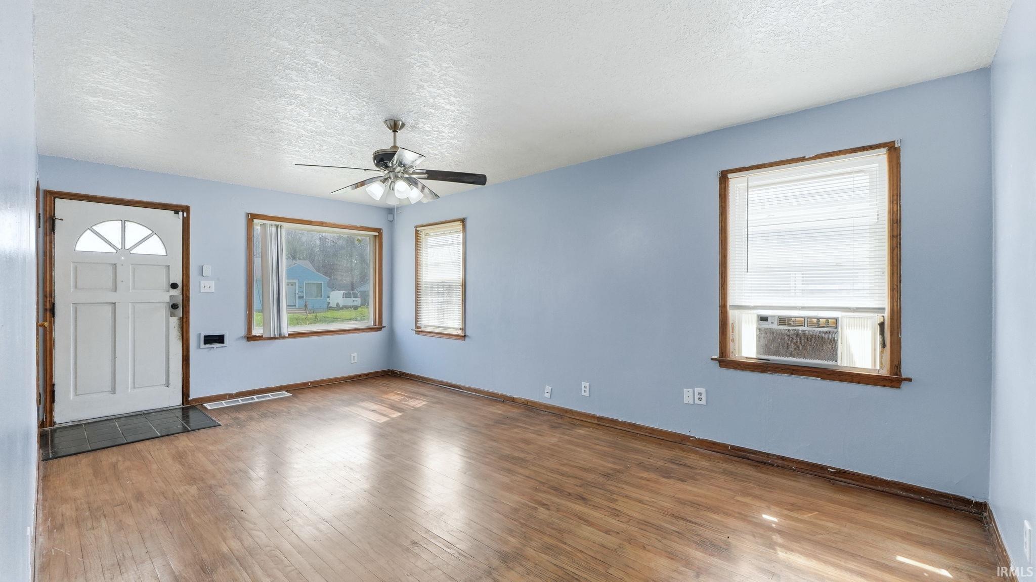 Entryway featuring a textured ceiling, a ceiling fan, hardwood / wood-style floors, and cooling unit