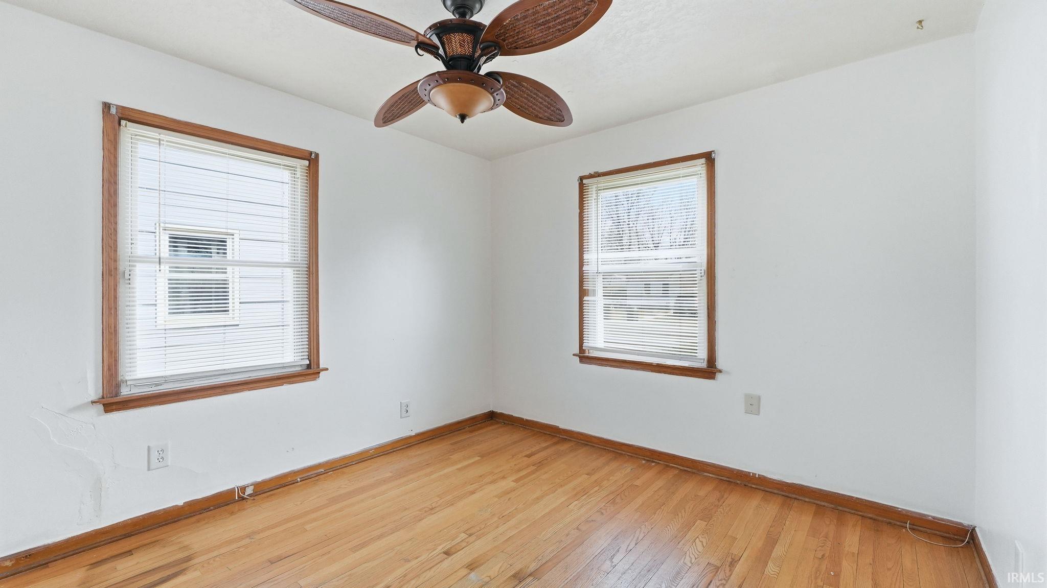 Empty room with light wood-style floors and ceiling fan