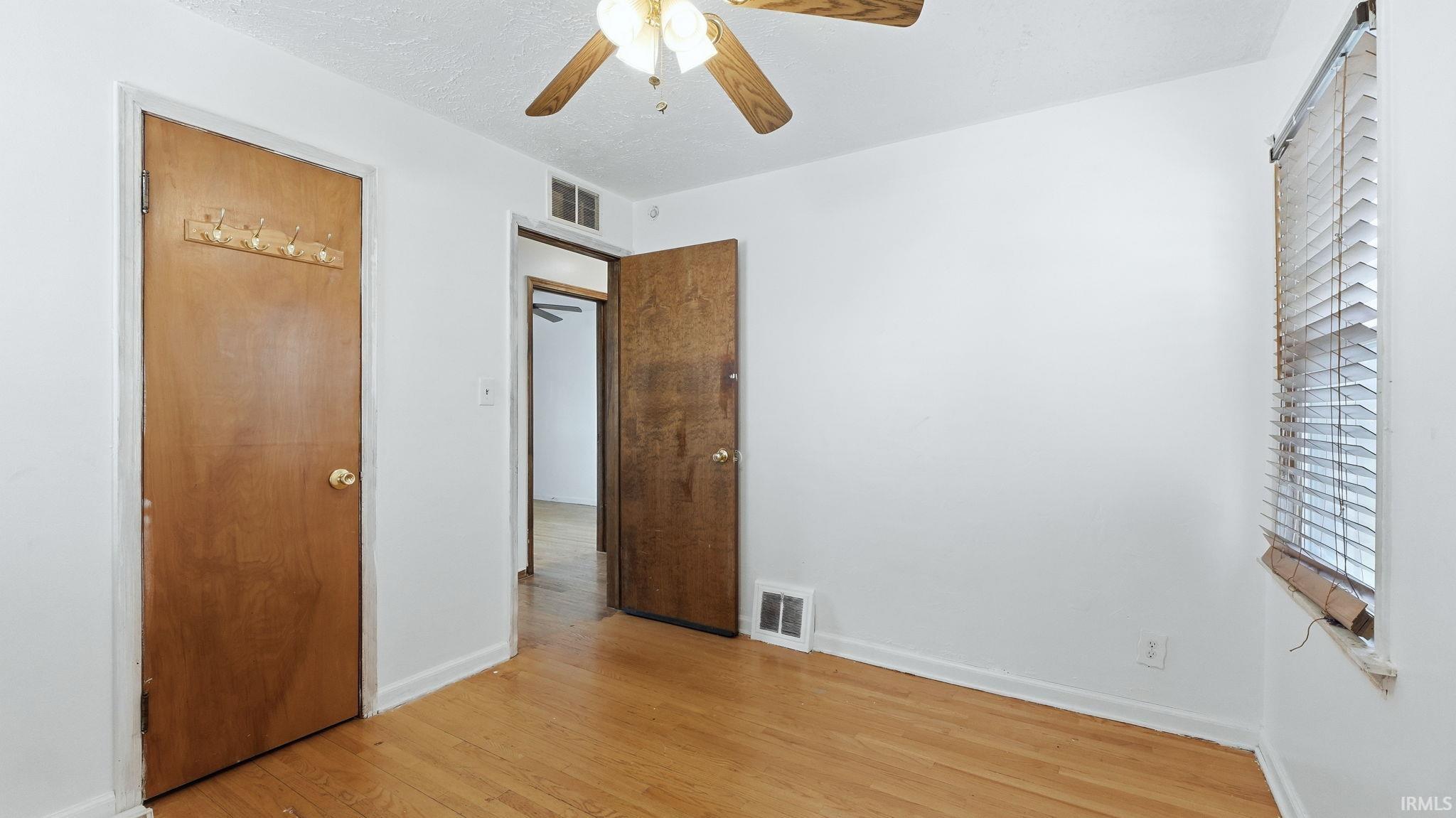 Unfurnished bedroom featuring light wood-style flooring, a closet, and ceiling fan