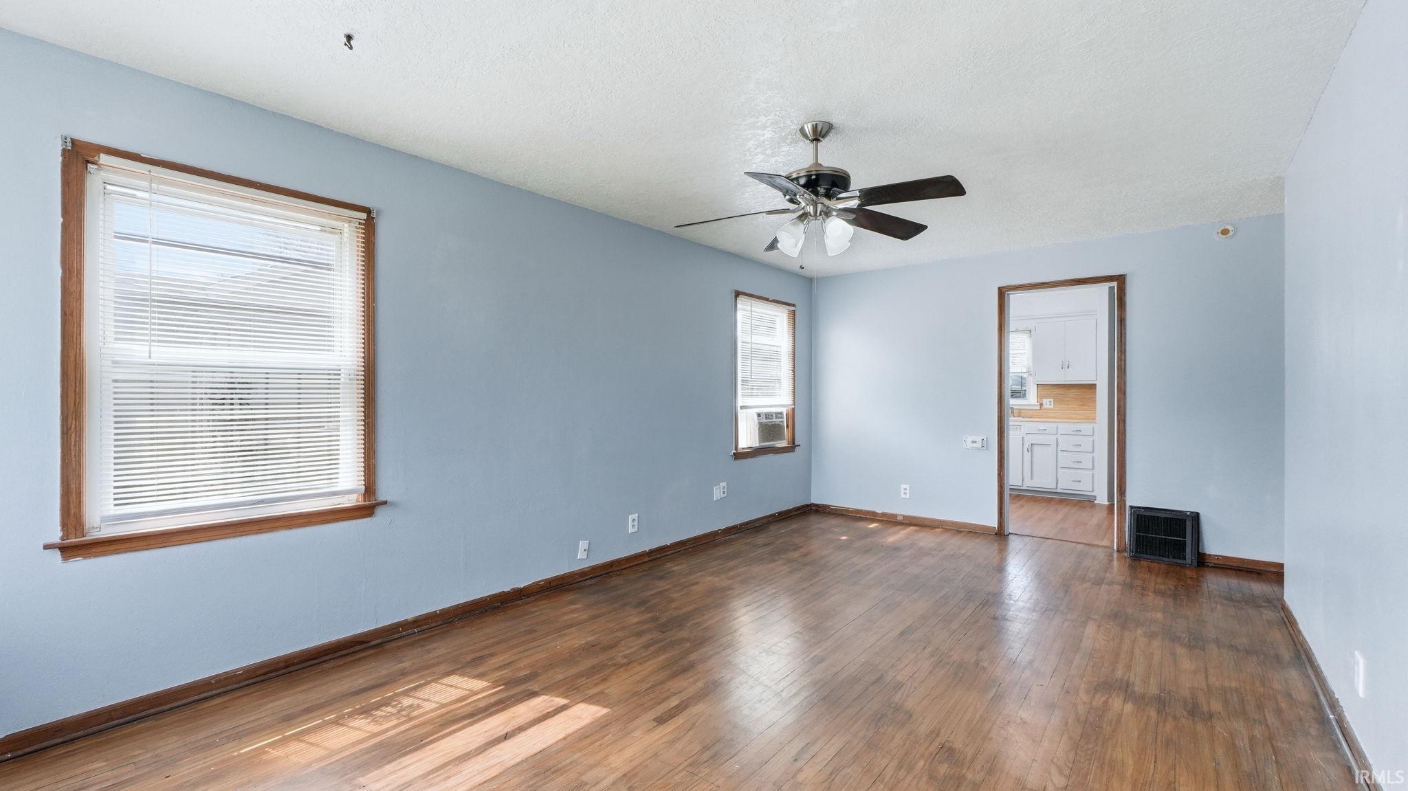 Unfurnished bedroom featuring dark wood-style flooring, a ceiling fan, ensuite bath, and a textured ceiling