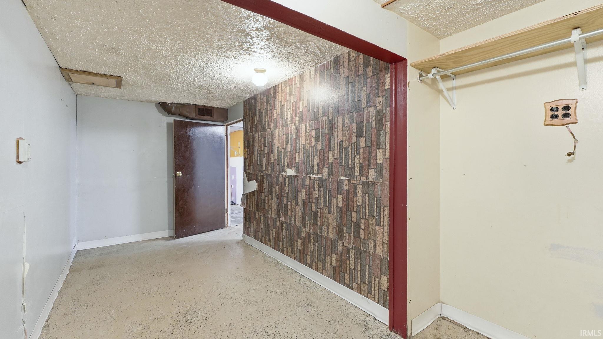 Basement with a textured ceiling and baseboards