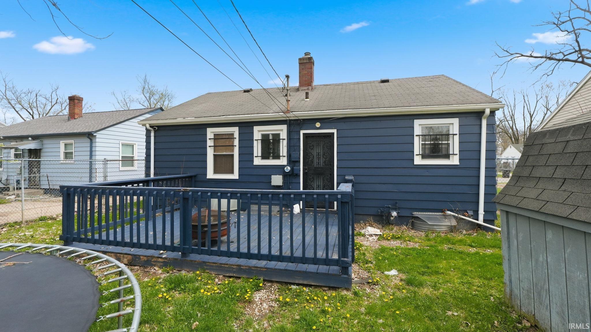 Rear view of property featuring a chimney, a deck, and roof with shingles