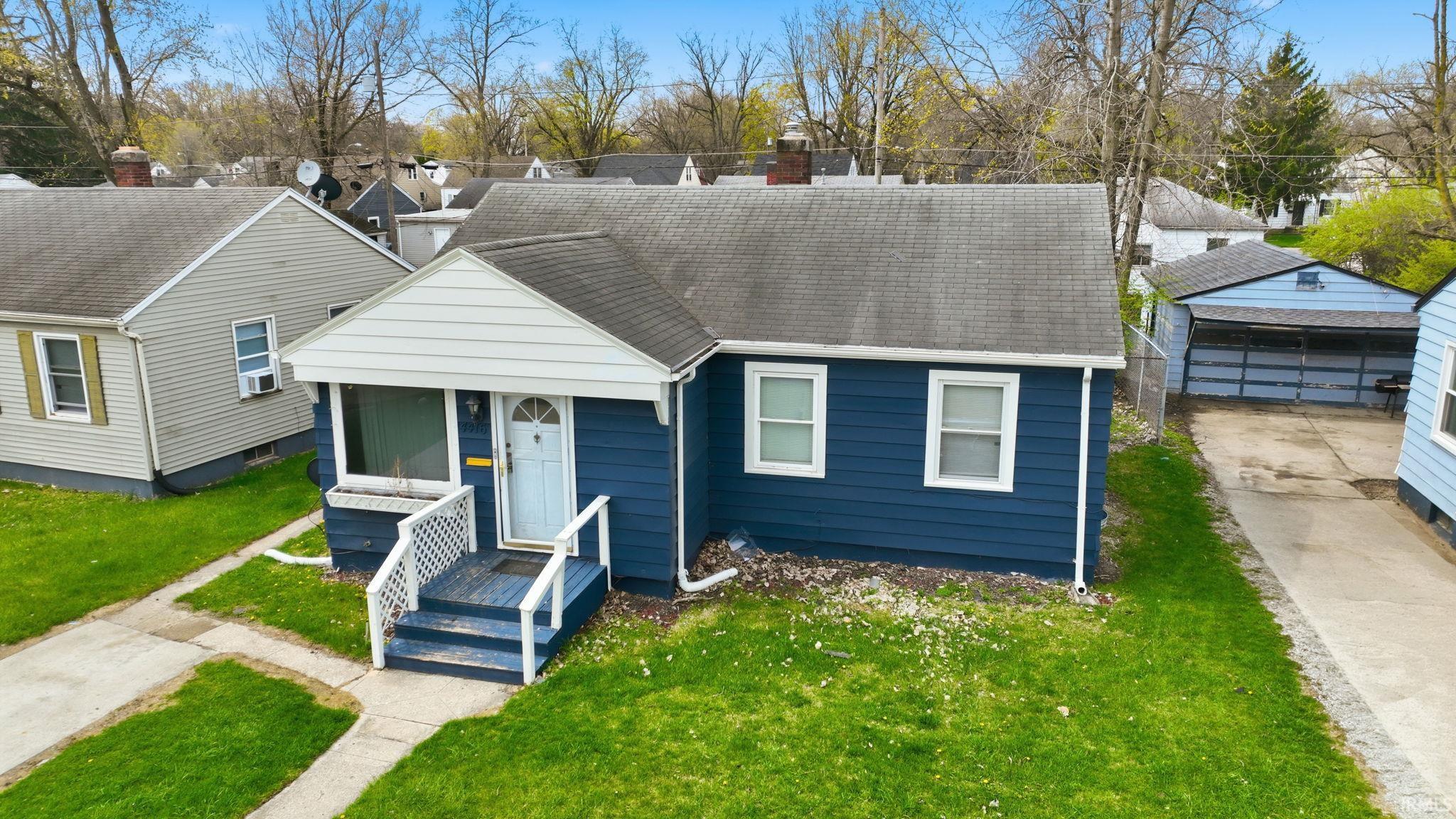 View of front of property featuring a shingled roof, a front yard, an outdoor structure, and a chimney