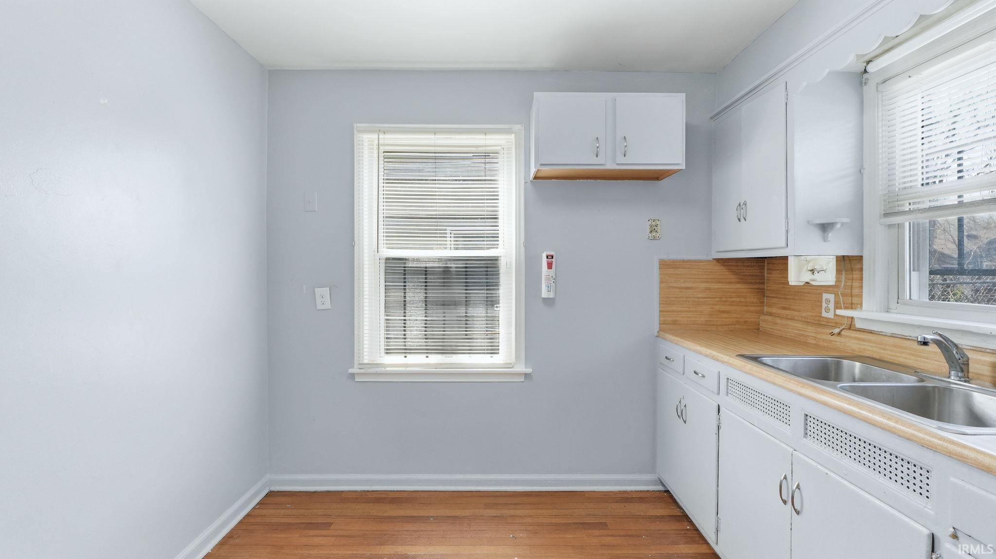 Kitchen with white cabinets, light countertops, light wood-style floors, and tasteful backsplash