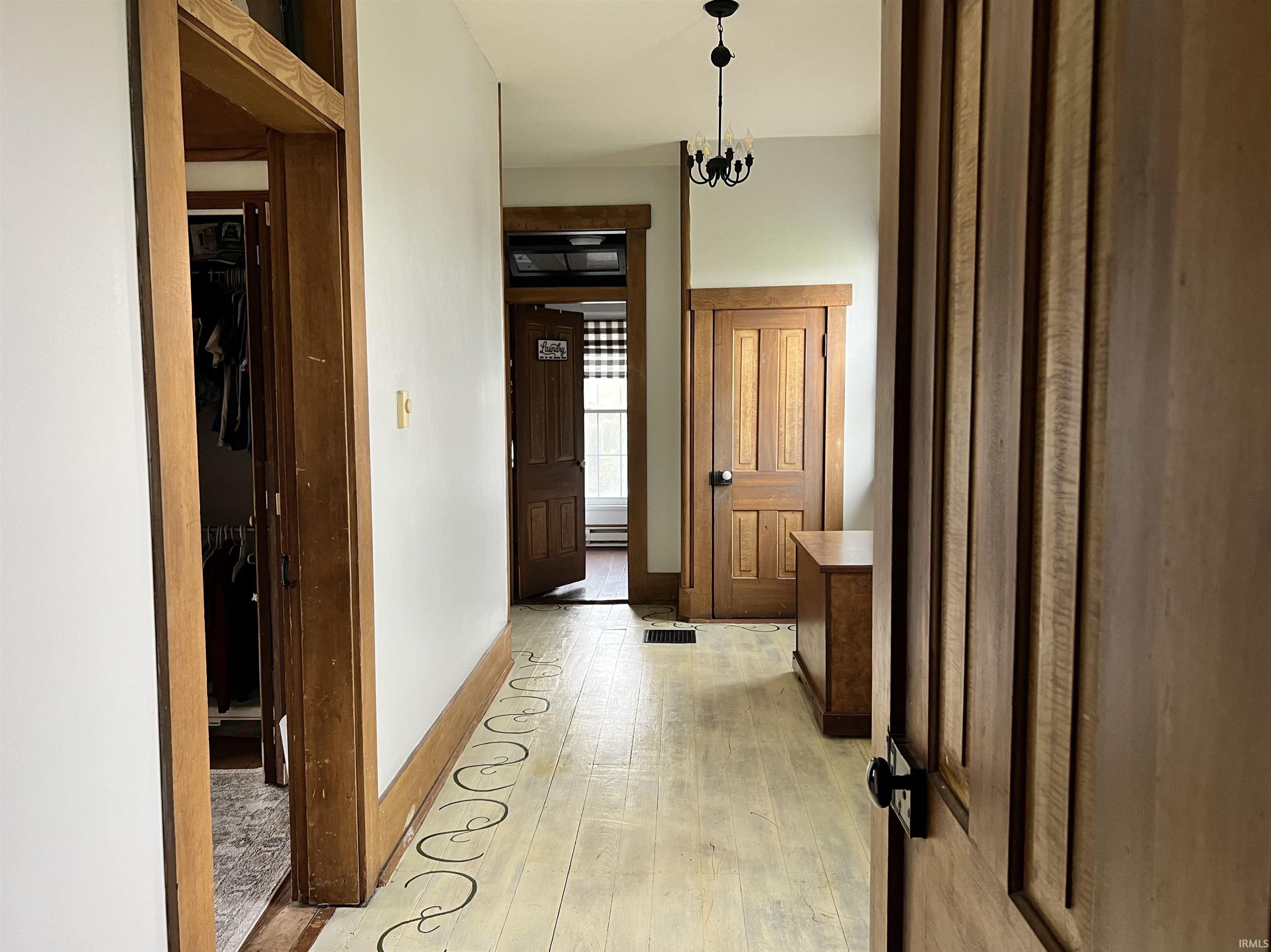 Corridor featuring light wood-style floors and suspended lighting