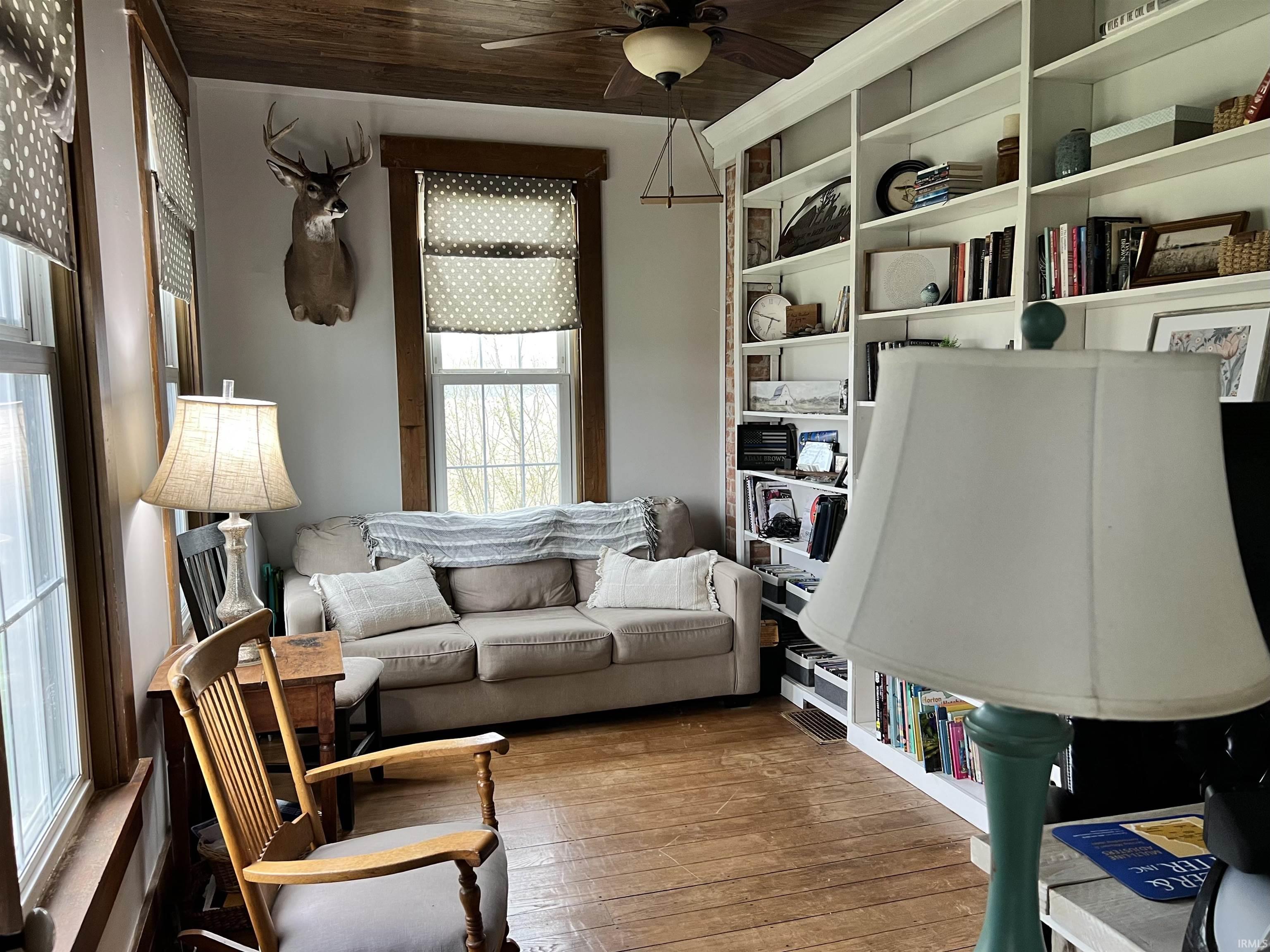 Living room featuring ceiling fan, hardwood / wood-style floors, and wood ceiling