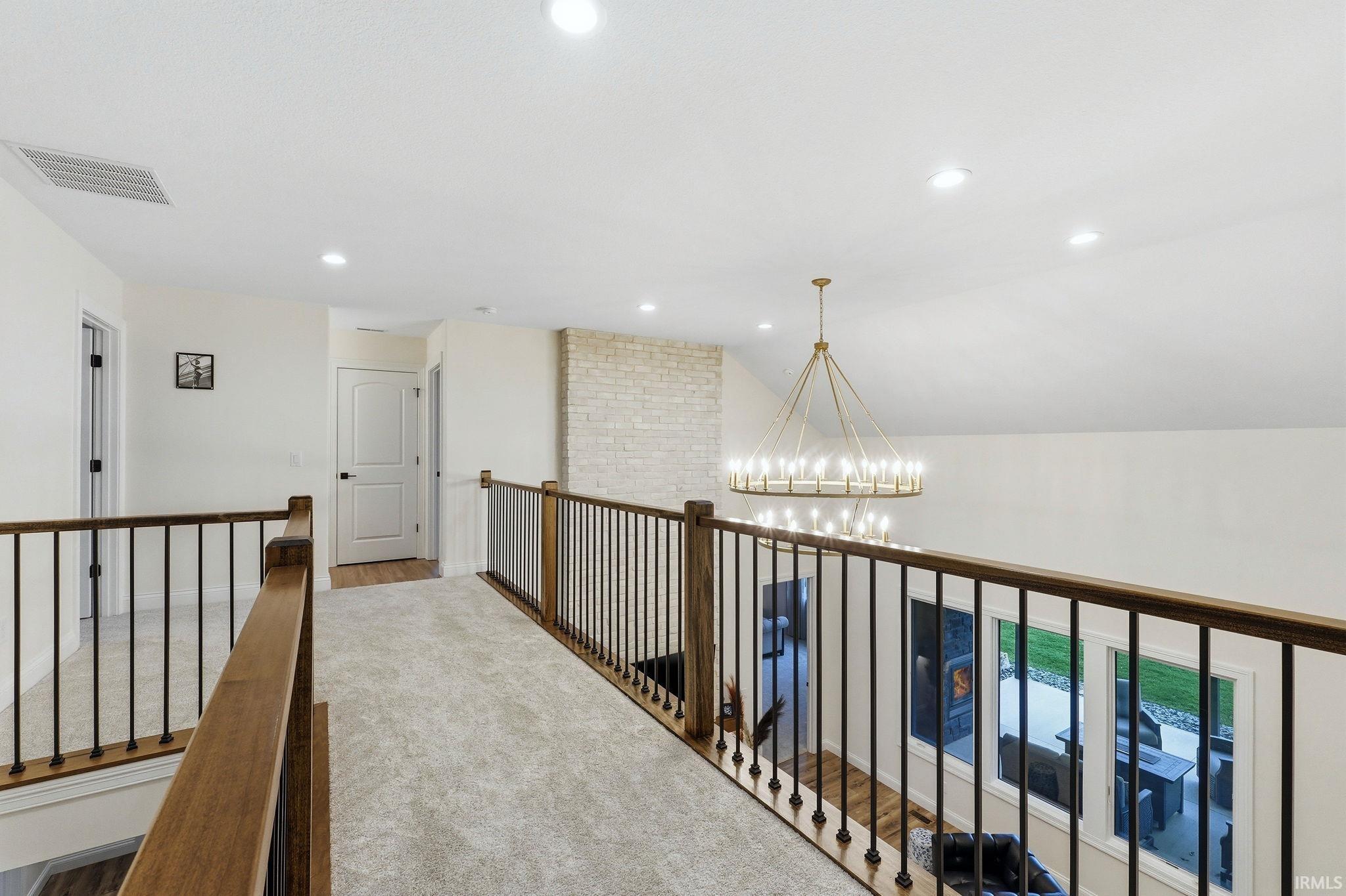 Hall with suspended lighting, lofted ceiling, and carpet floors
