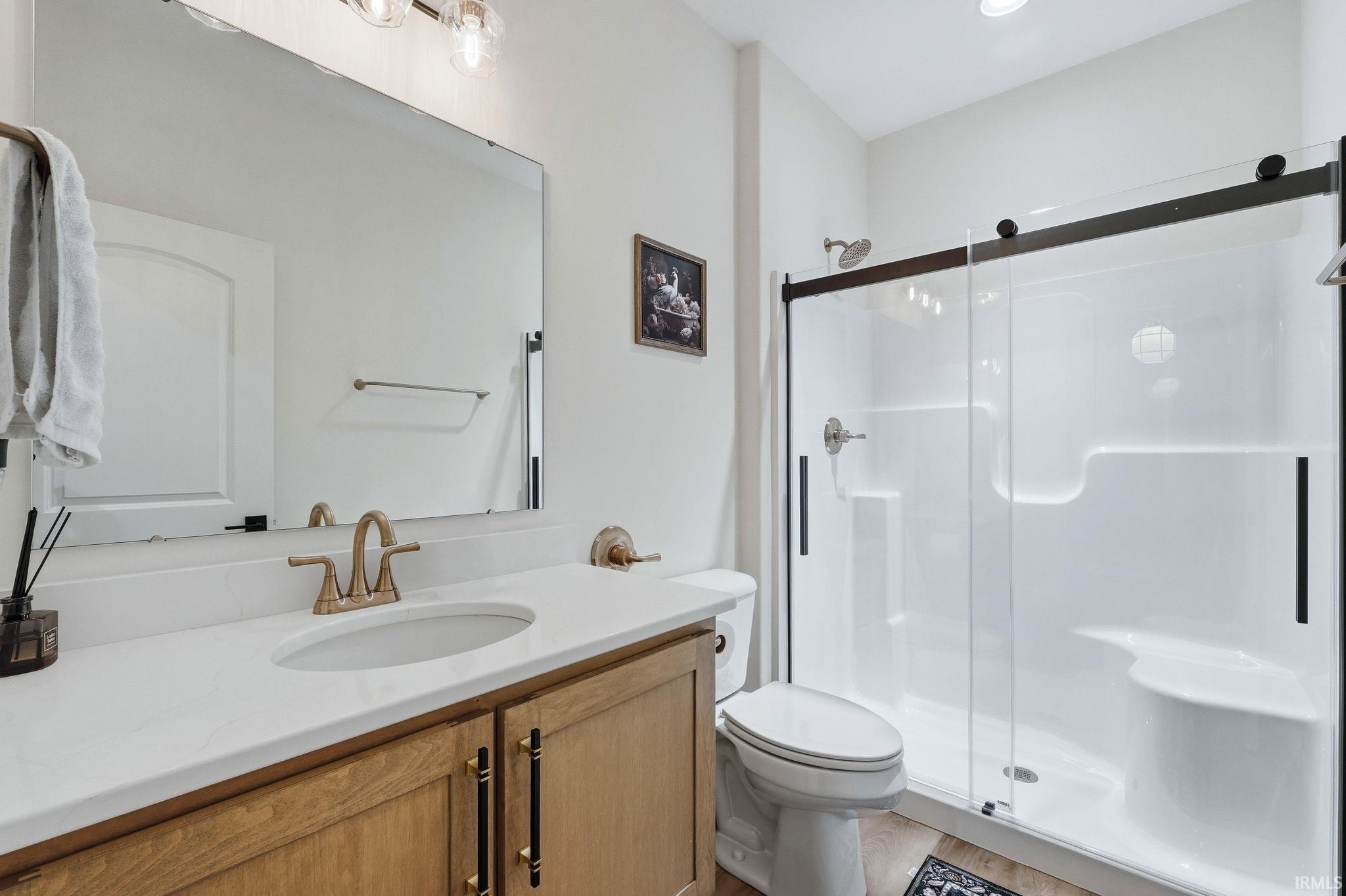 Full bath featuring a stall shower, vanity, and light wood-style floors