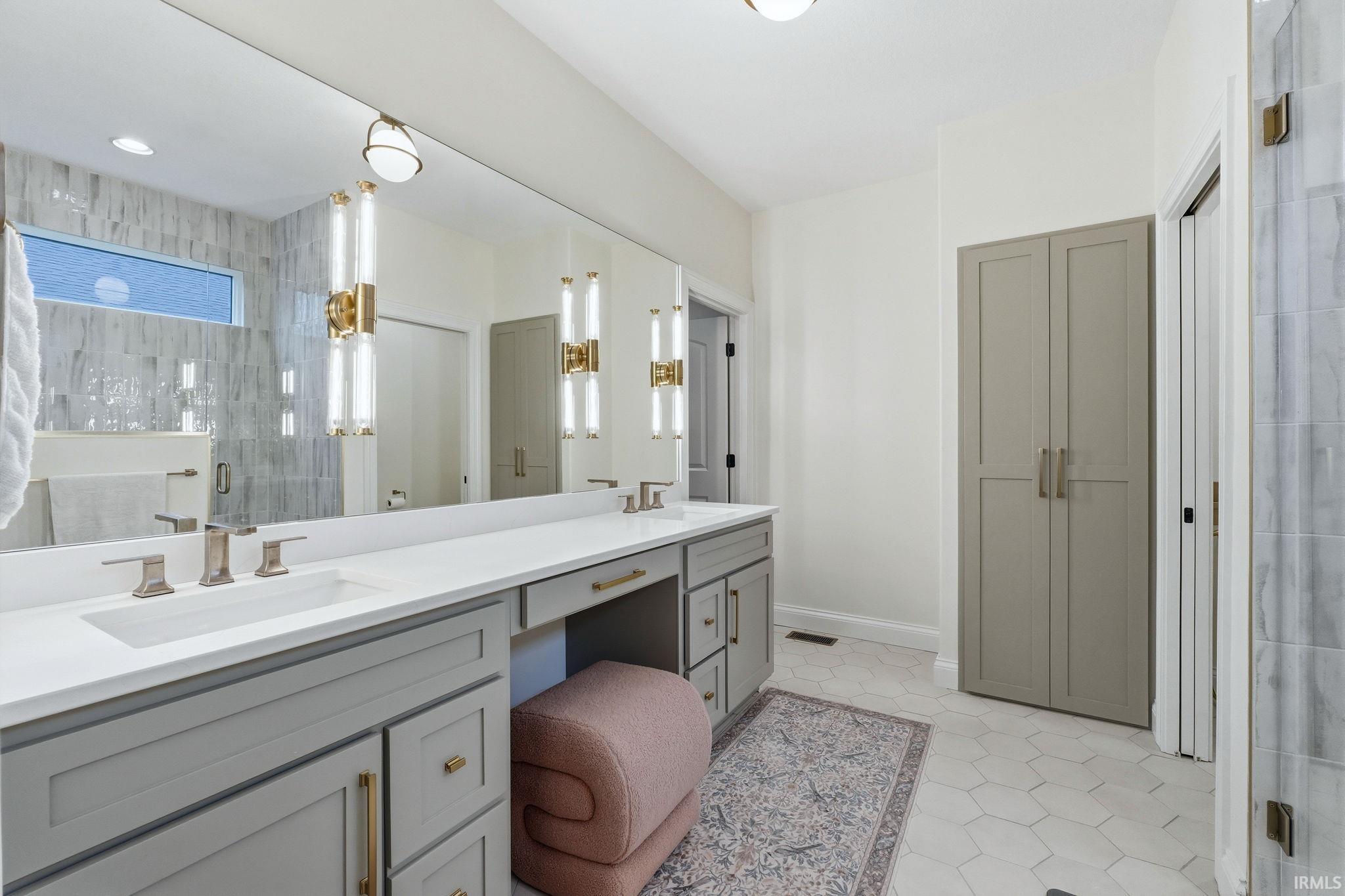 Full bathroom featuring a stall shower, double vanity, light tile patterned floors, and a closet