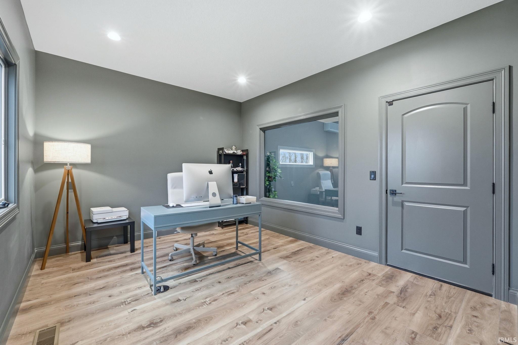 Office area featuring light wood-style floors and recessed lighting