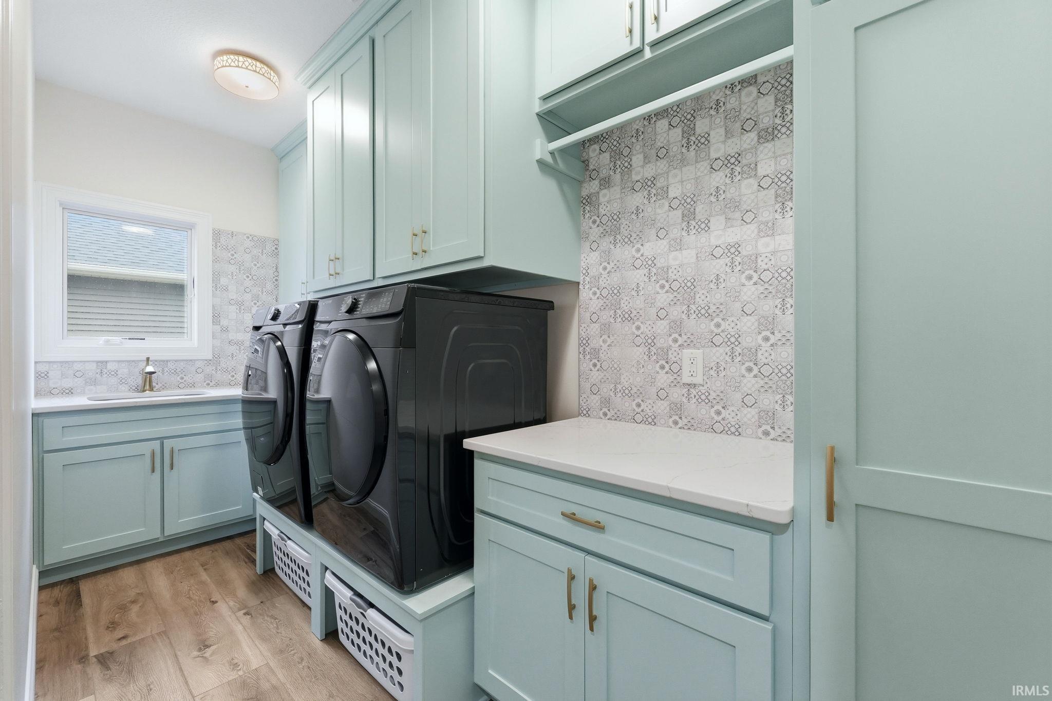 Laundry area with cabinet space, separate washer and dryer, and light wood-style flooring