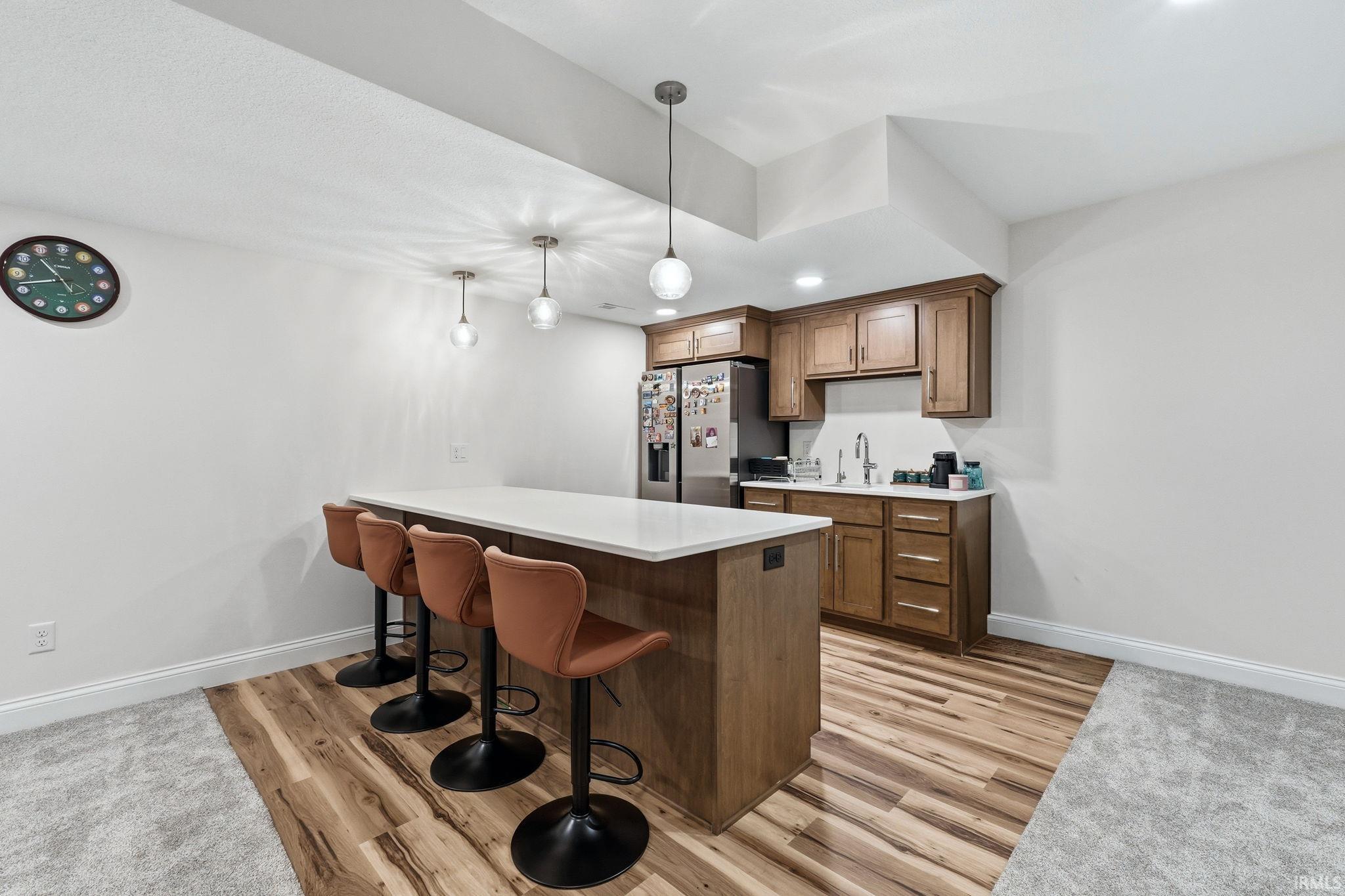 Kitchen with a breakfast bar area, wood finish cabinetry, a peninsula, and light wood-style flooring