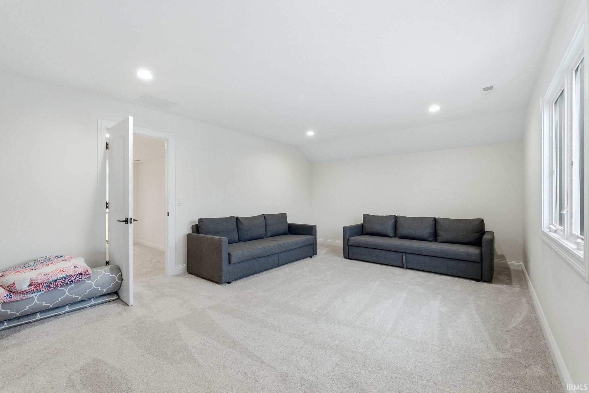 Living area featuring lofted ceiling, recessed lighting, and light colored carpet