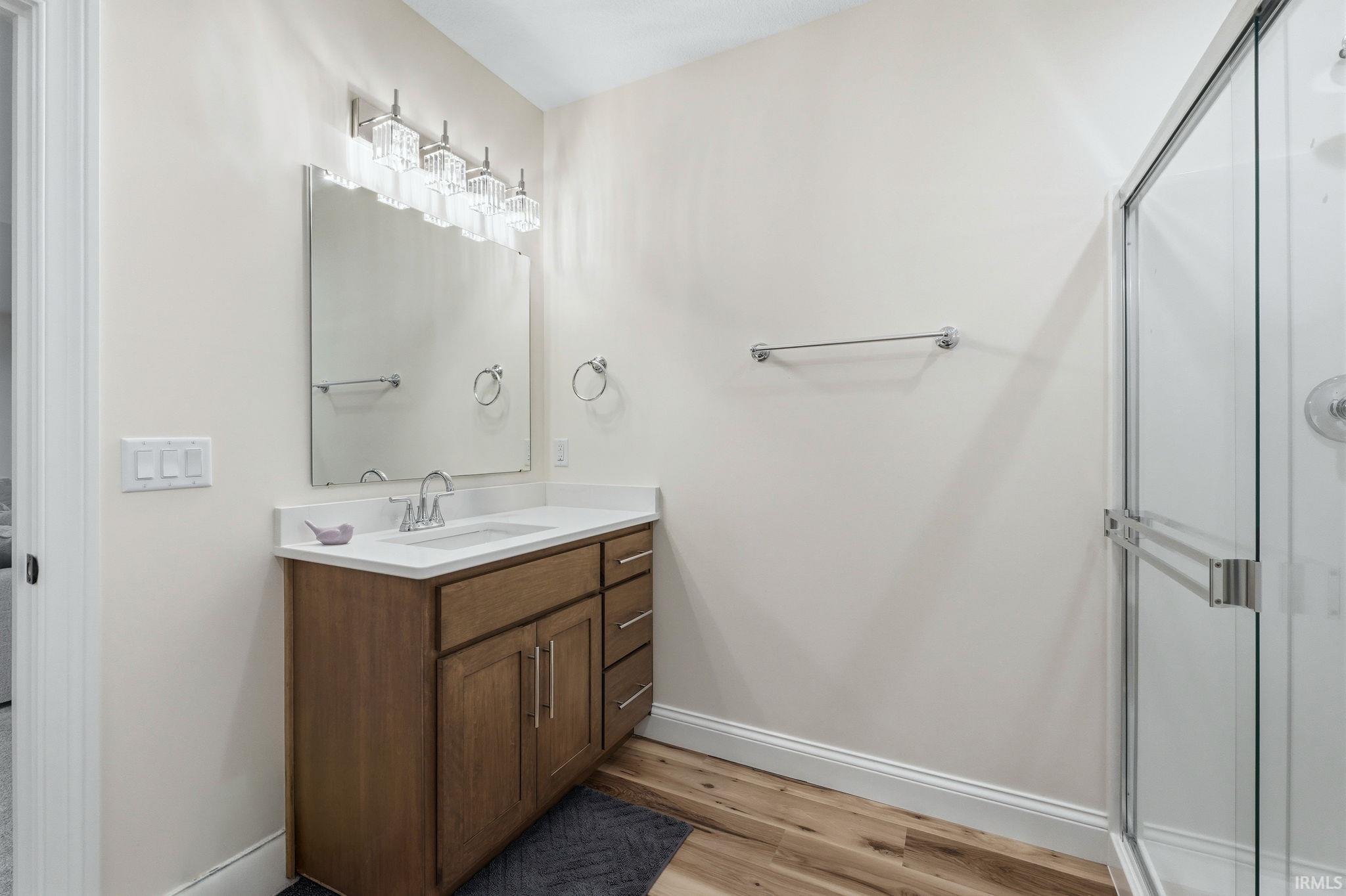 Full bathroom featuring vanity, a shower stall, and light wood-style floors