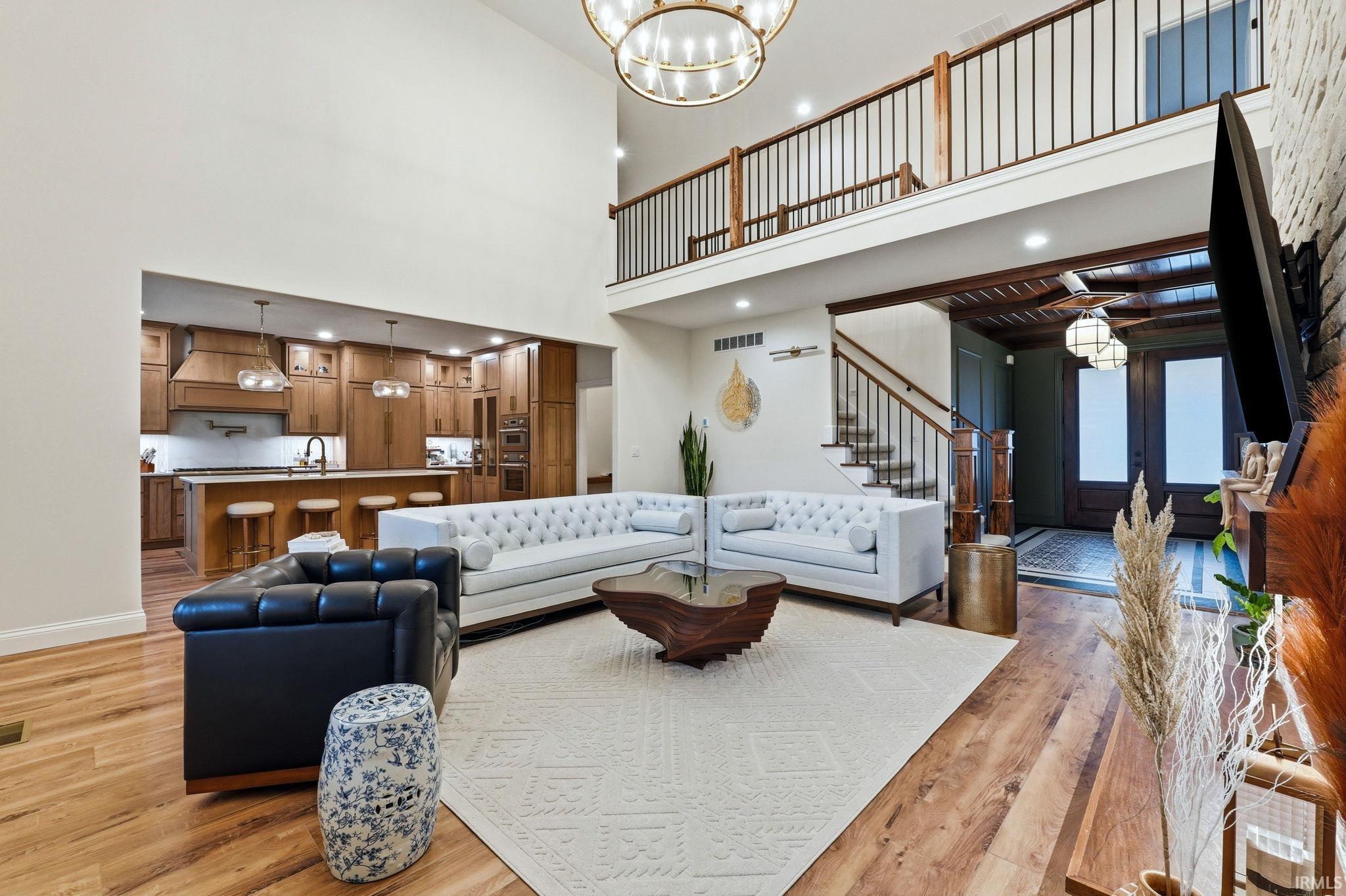 Living room featuring a chandelier, light wood-type flooring, and a high ceiling