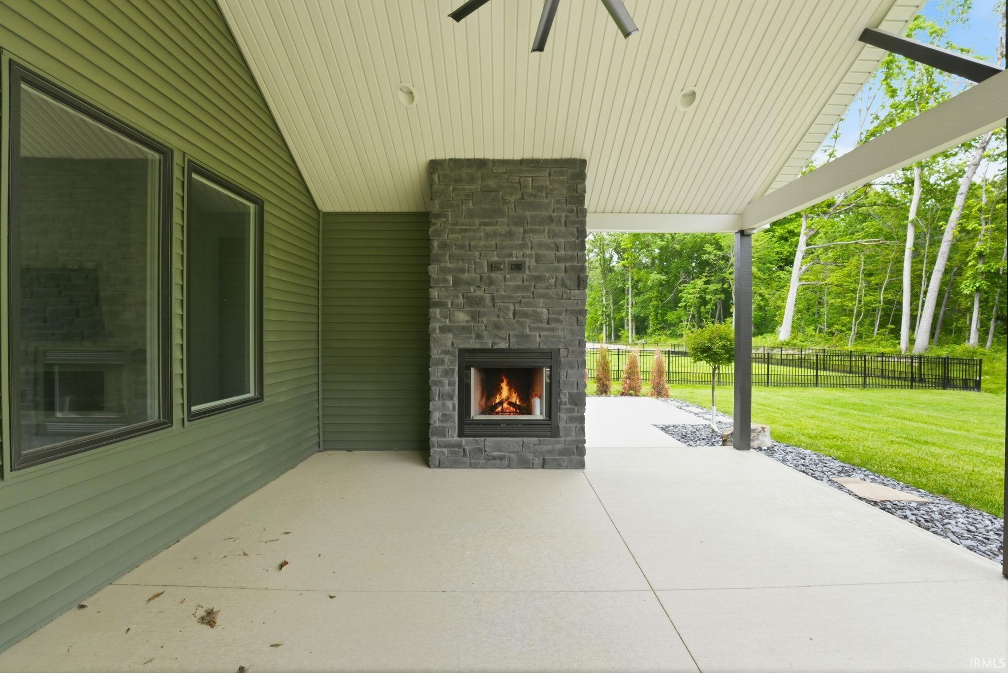 Covered patio with a stone-clad fireplace and recessed lighting