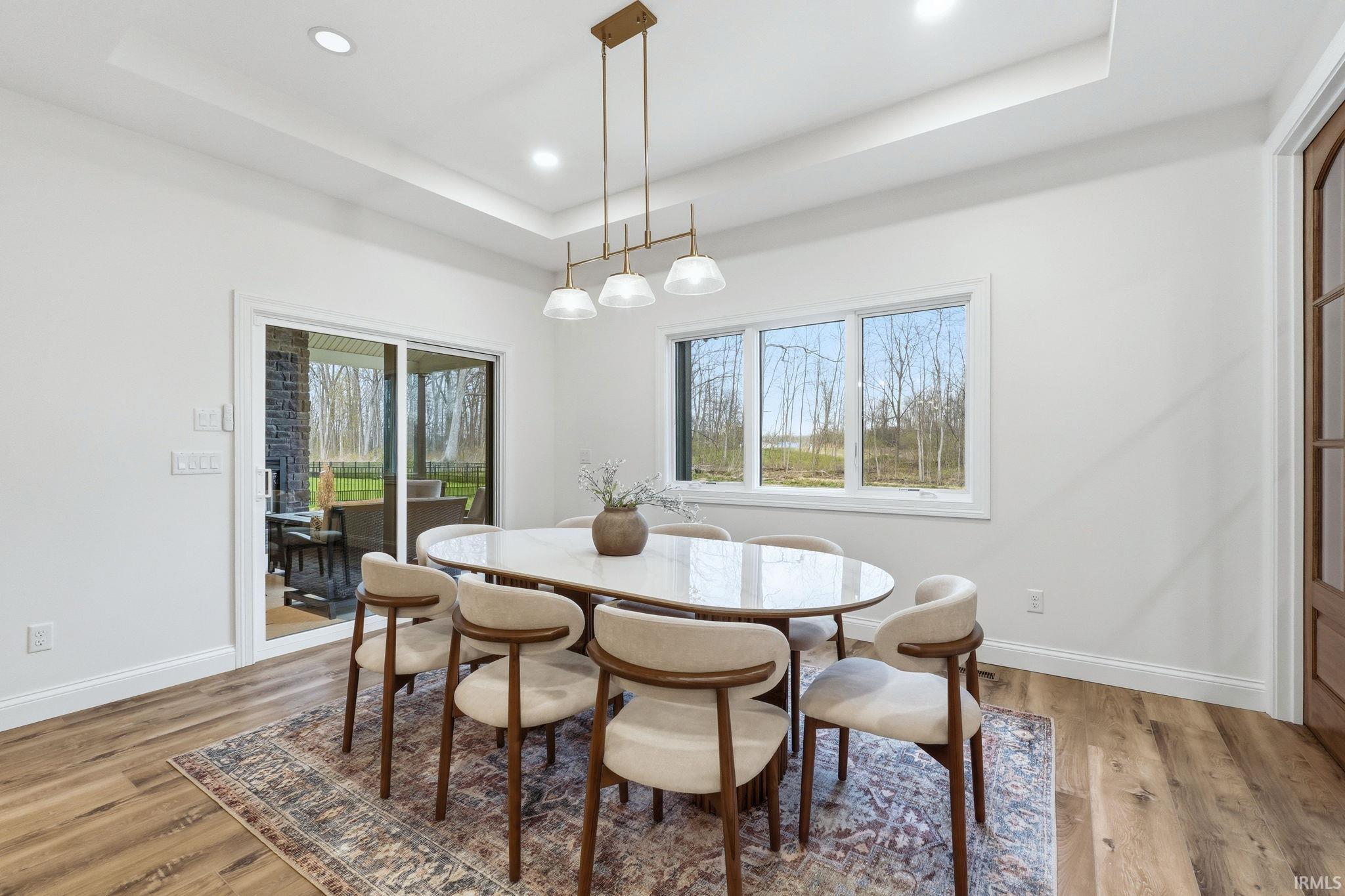 Dining space with a tray ceiling, light wood-style flooring, and recessed lighting