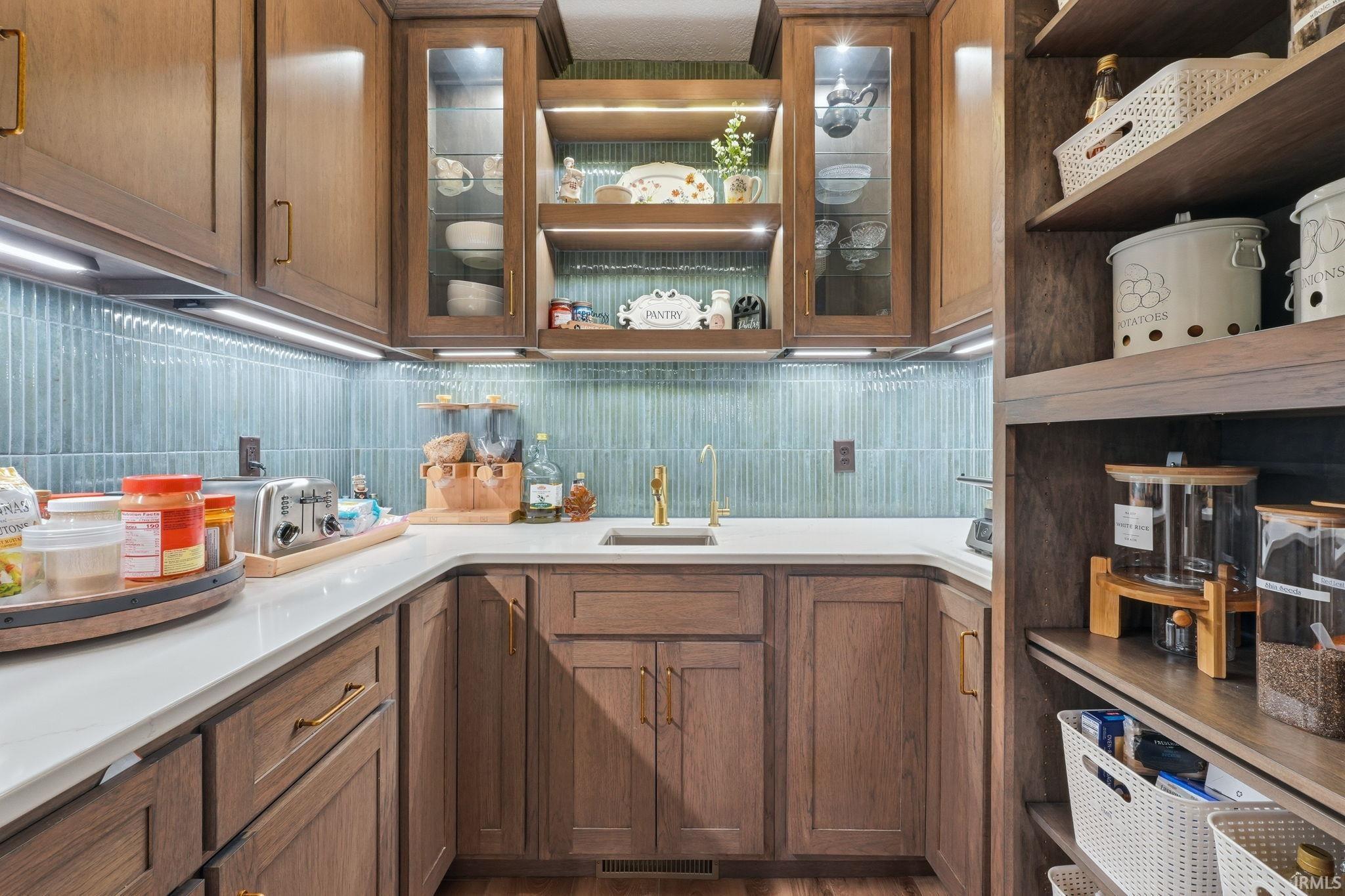 Kitchen with wood finish cabinets, glass fronted cabinets, and tasteful backsplash