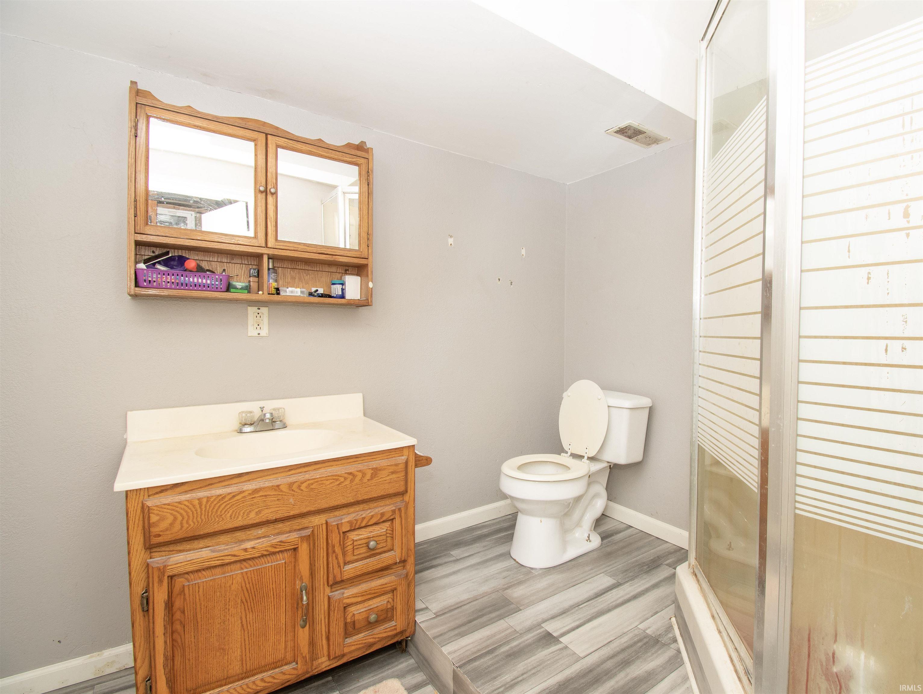 Bathroom with vanity, a stall shower, and light wood finished floors