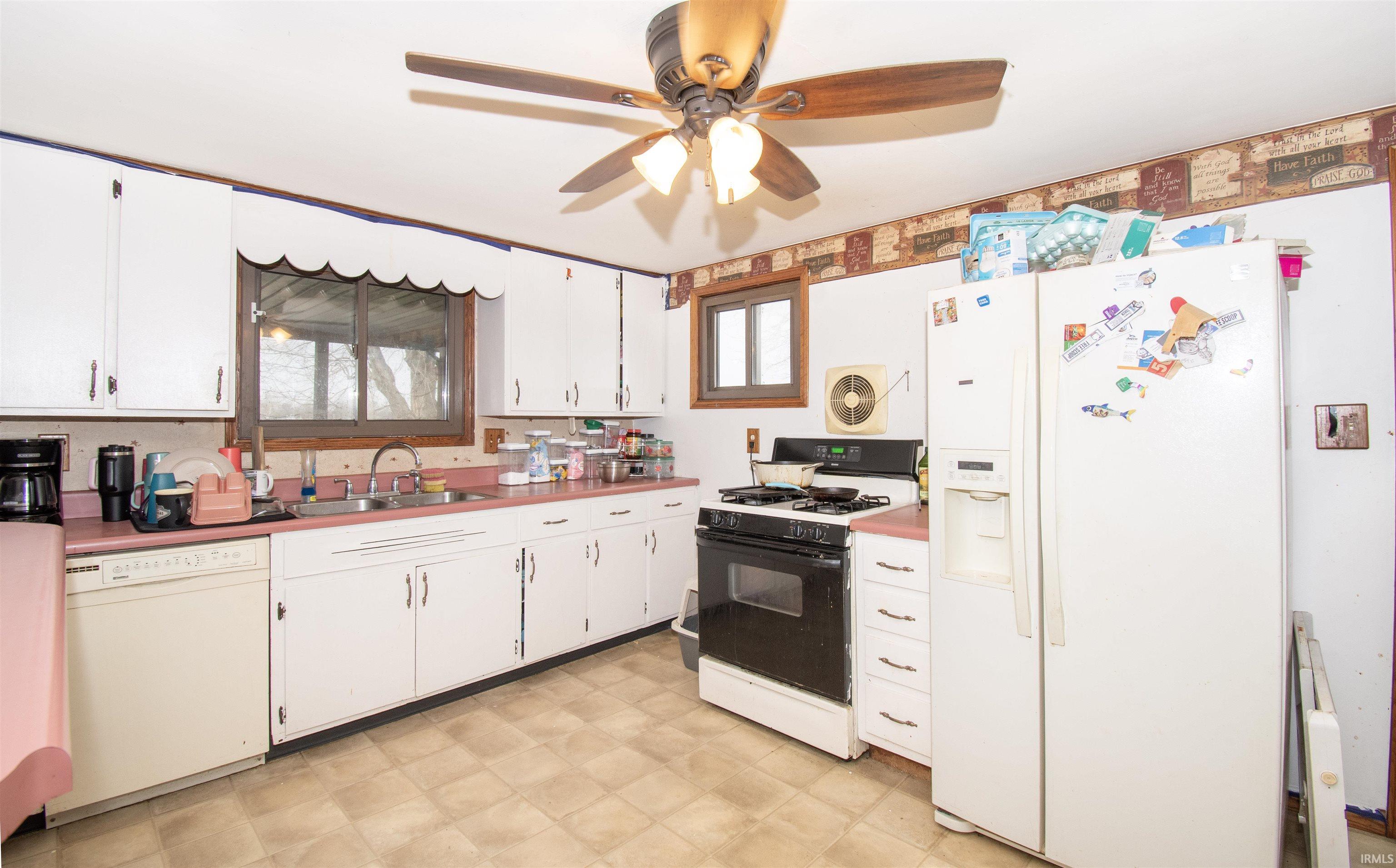 Kitchen featuring white appliances, light flooring, white cabinetry, and a ceiling fan