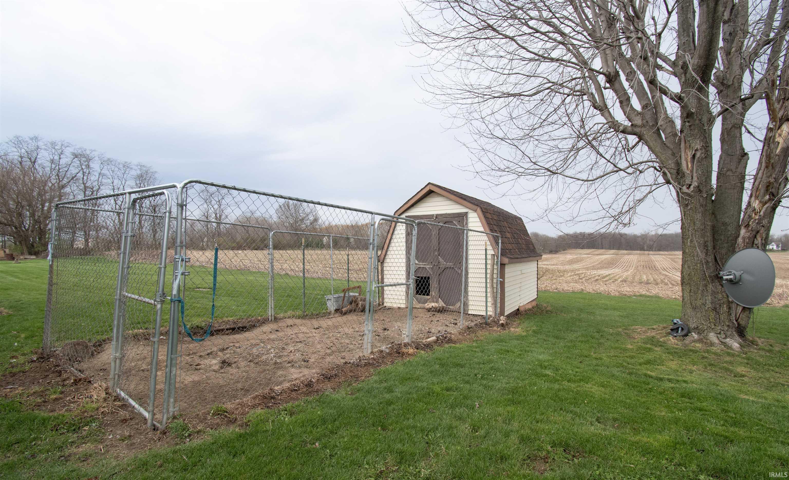 View of grassy yard with a gate, an outdoor structure, and a view of countryside