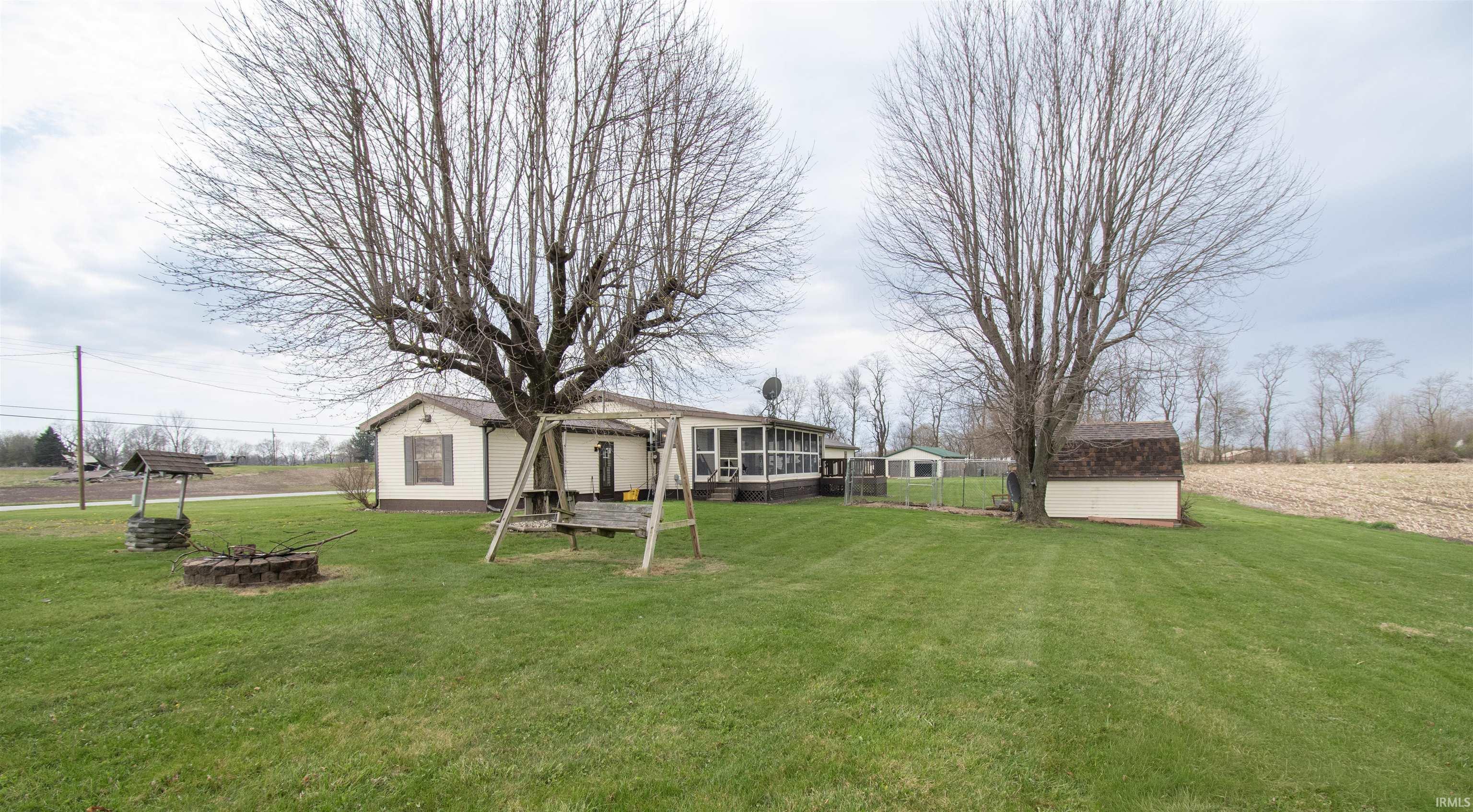 View of green lawn featuring a fire pit and a storage unit
