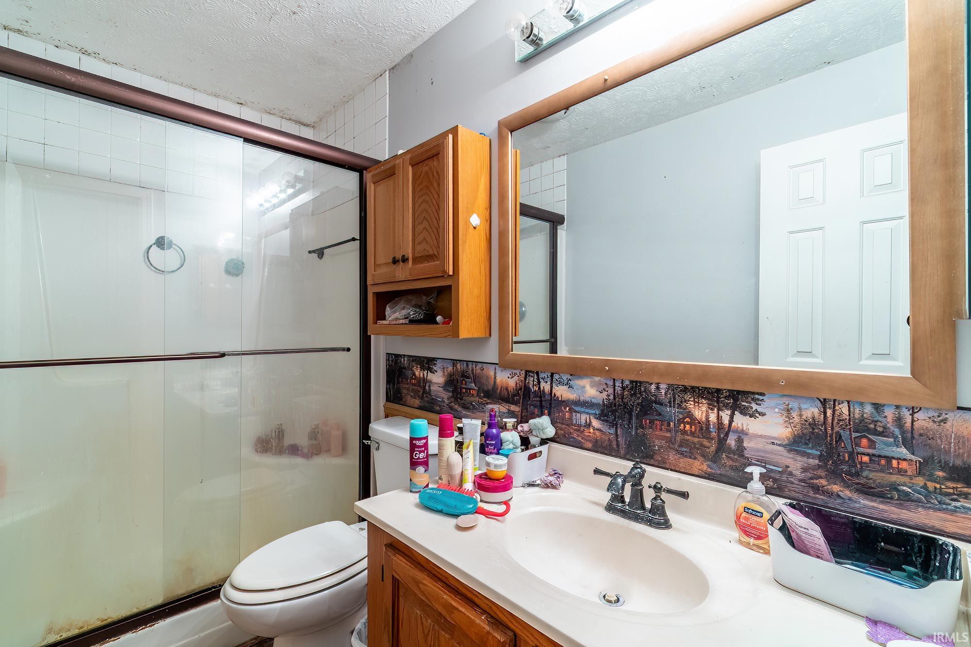 Full bath with vanity, a textured ceiling, and a stall shower