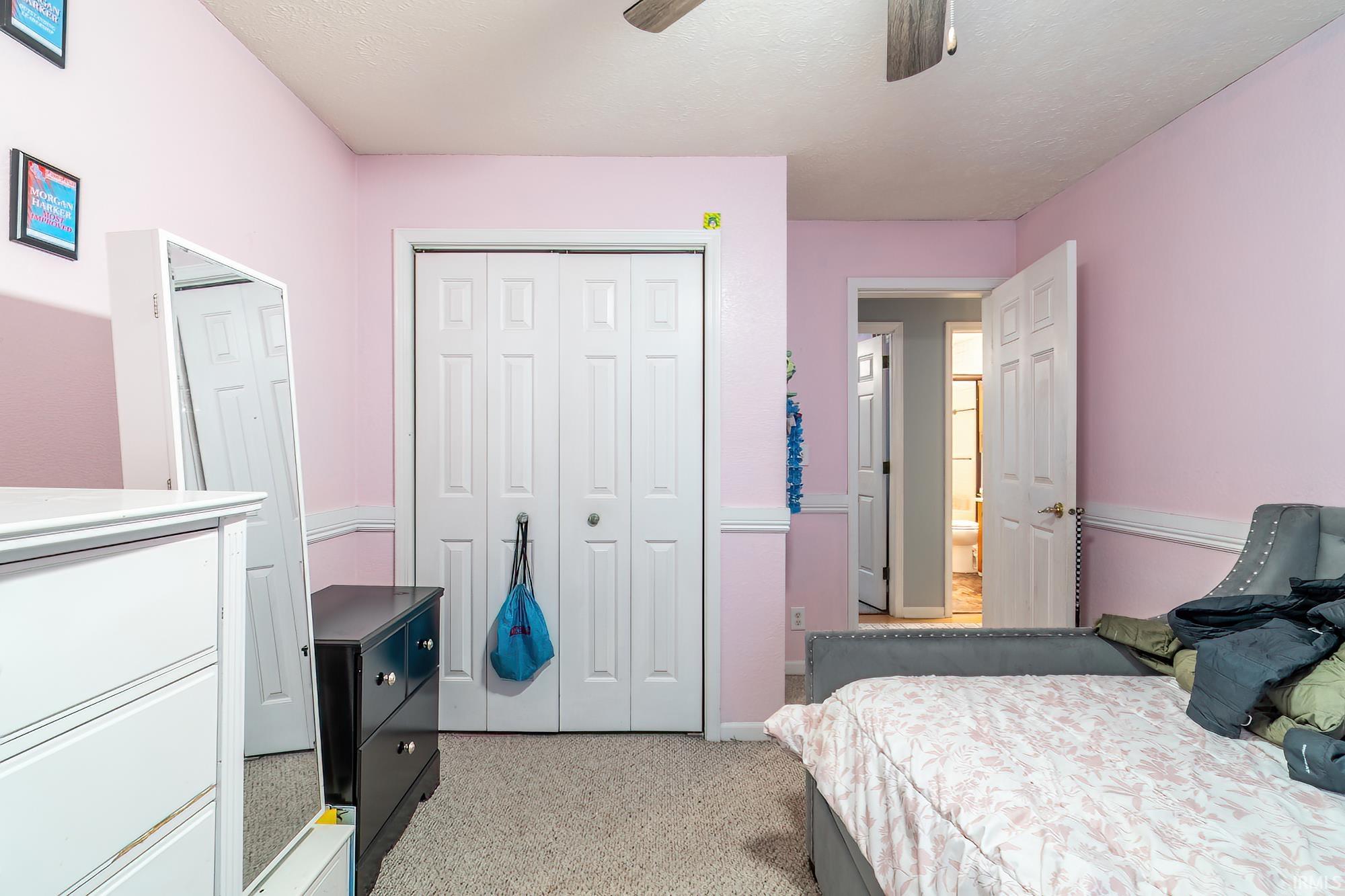 Bedroom featuring light carpet, a closet, a ceiling fan, and a textured ceiling