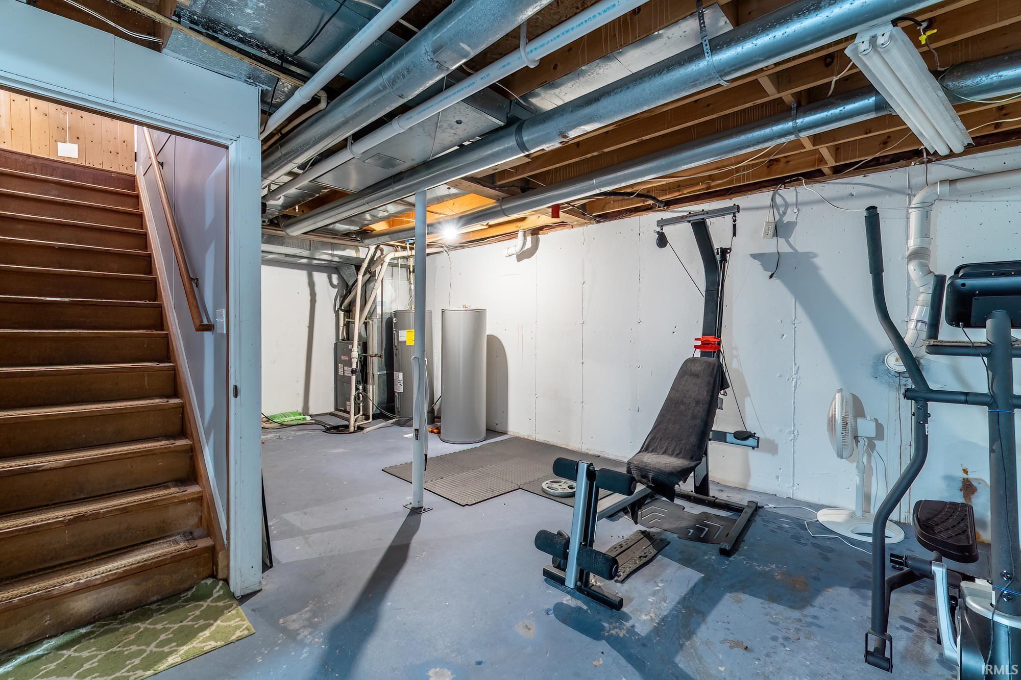 Workout room with concrete flooring, water heater, electric water heater, and heating unit