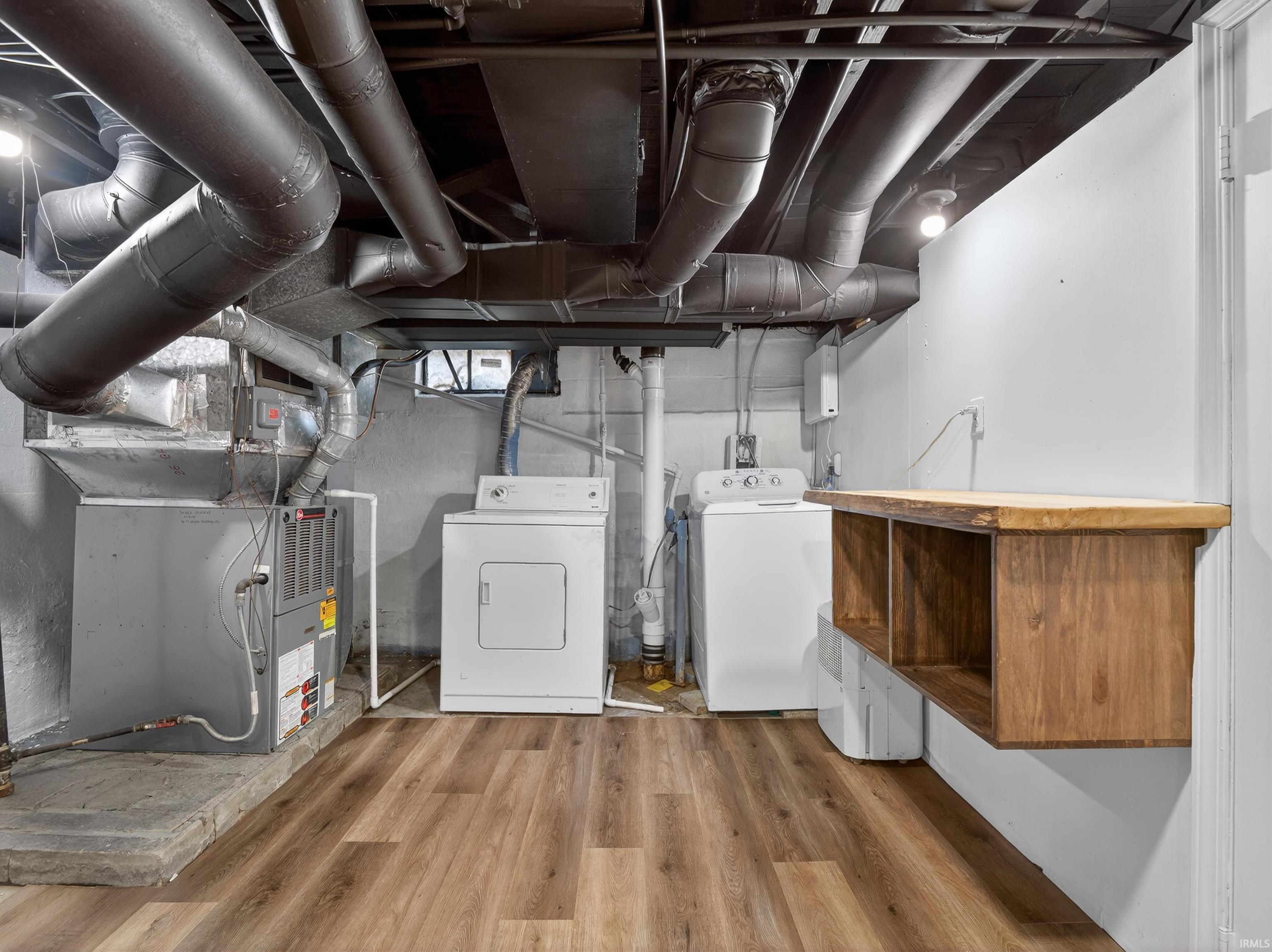 Below grade area with heating unit, wood finished floors, and washer and clothes dryer