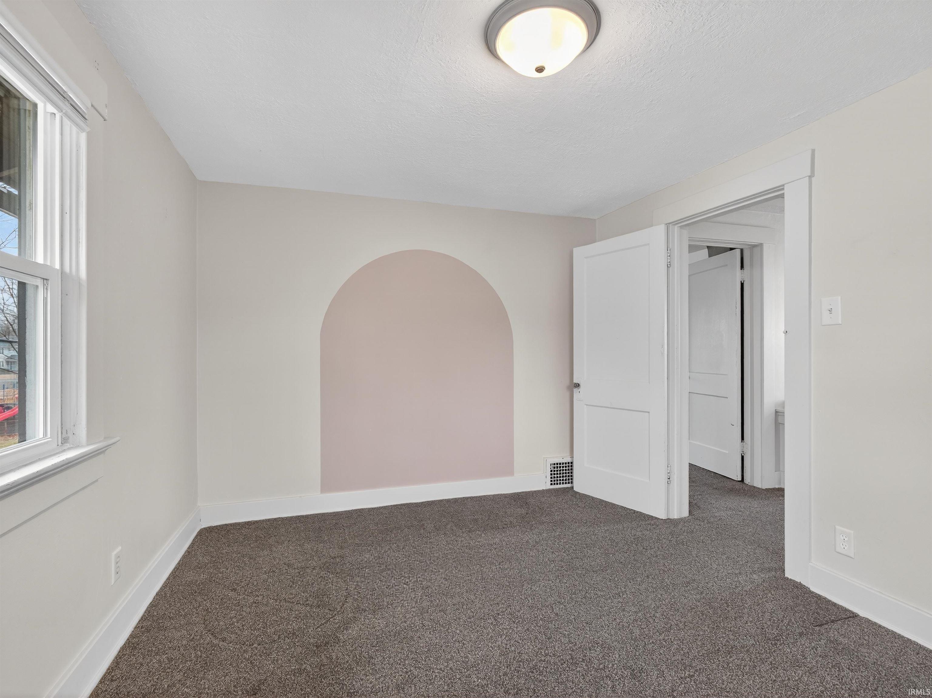 Unfurnished room with dark colored carpet and baseboards