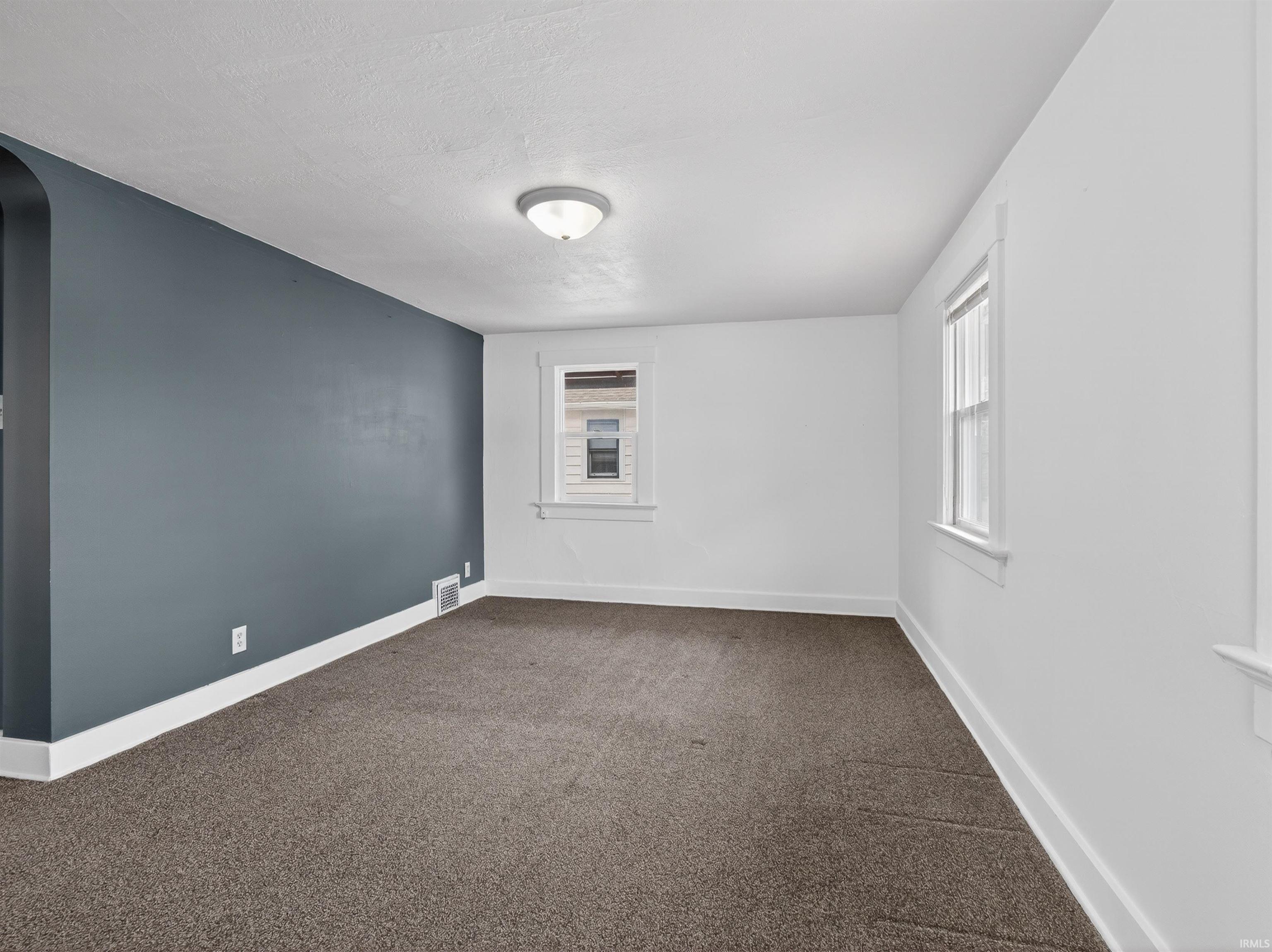 Spare room with dark colored carpet and a textured ceiling