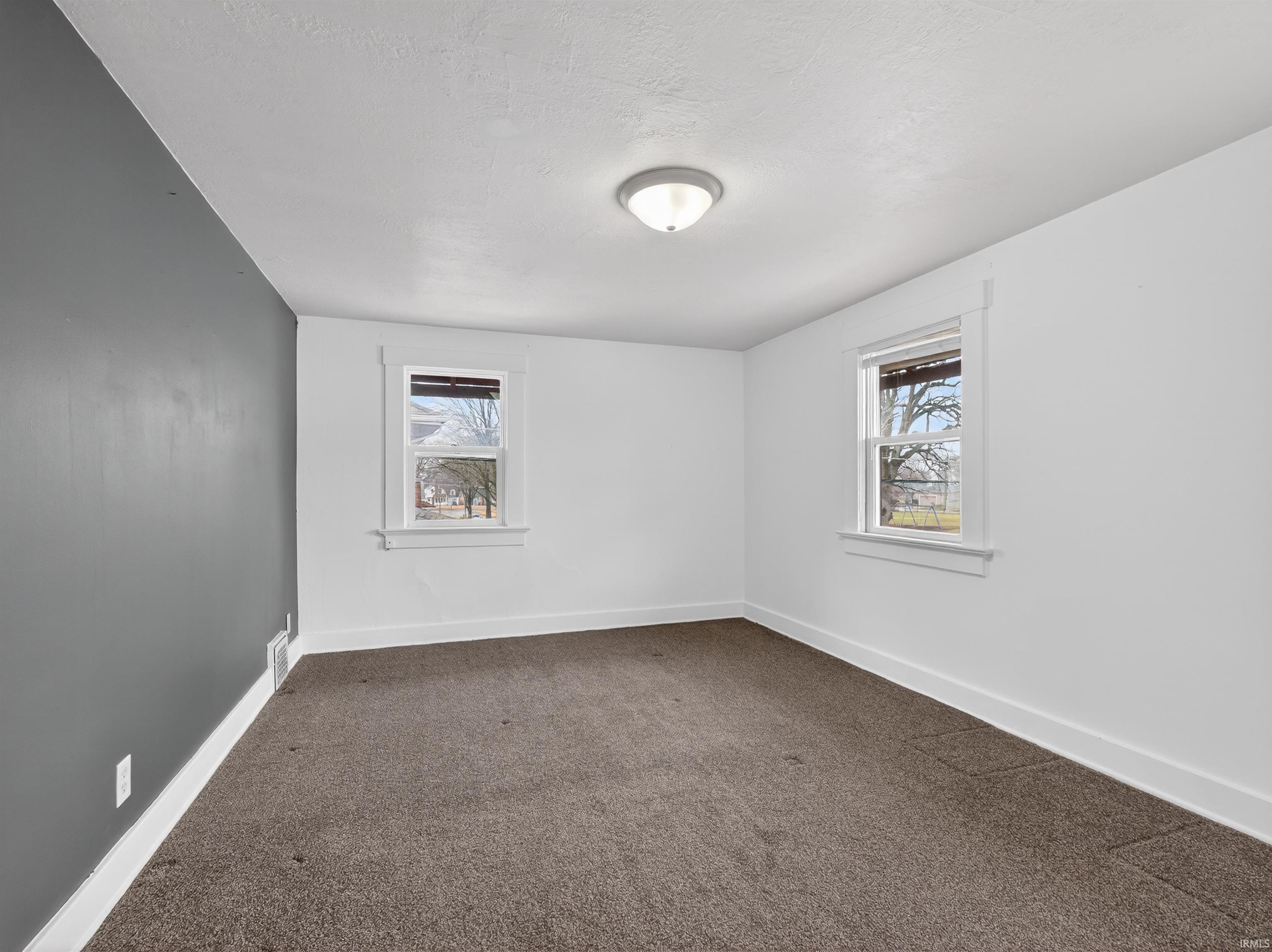 Spare room with baseboards and dark colored carpet