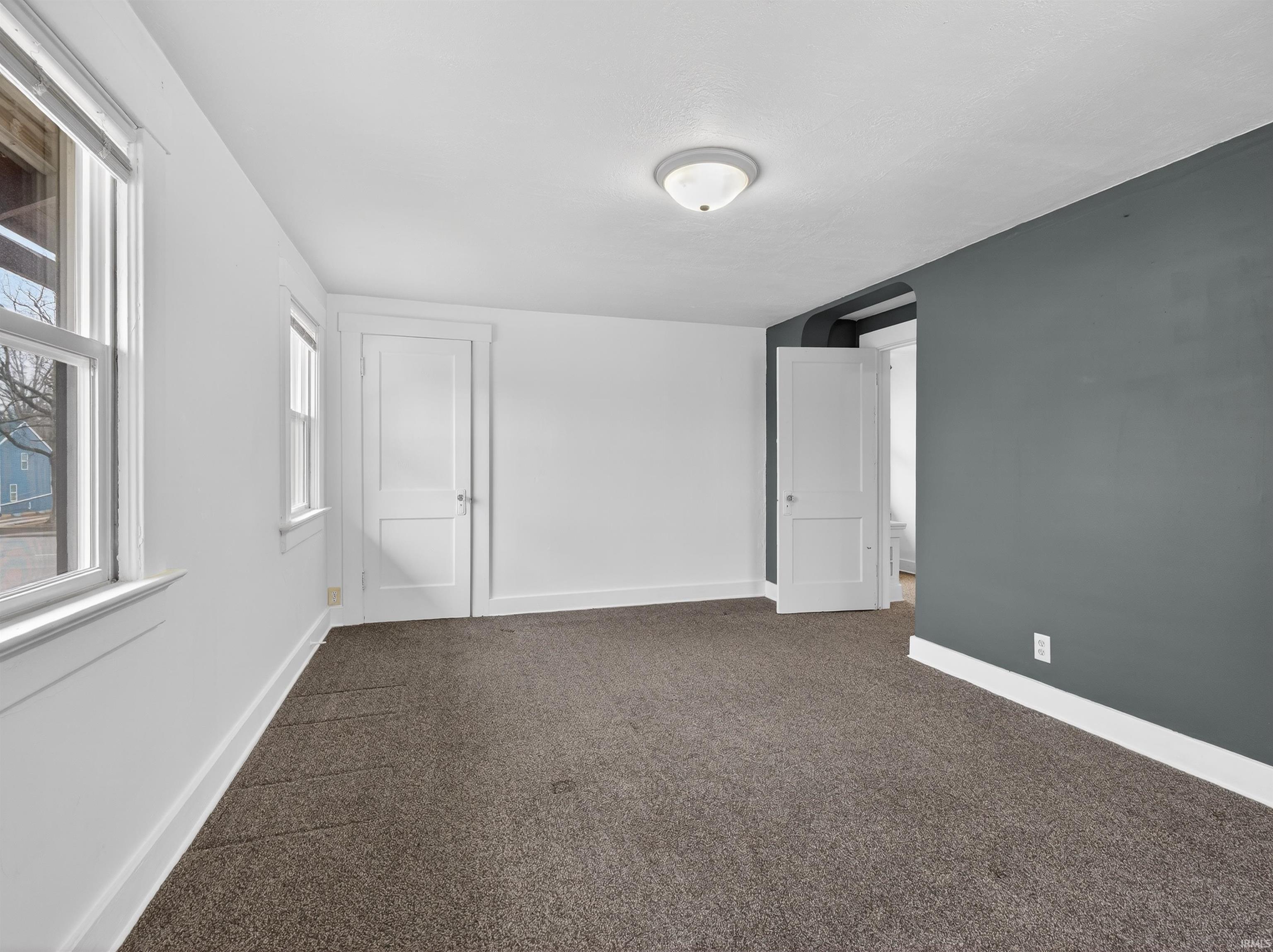 Unfurnished bedroom featuring baseboards and dark carpet