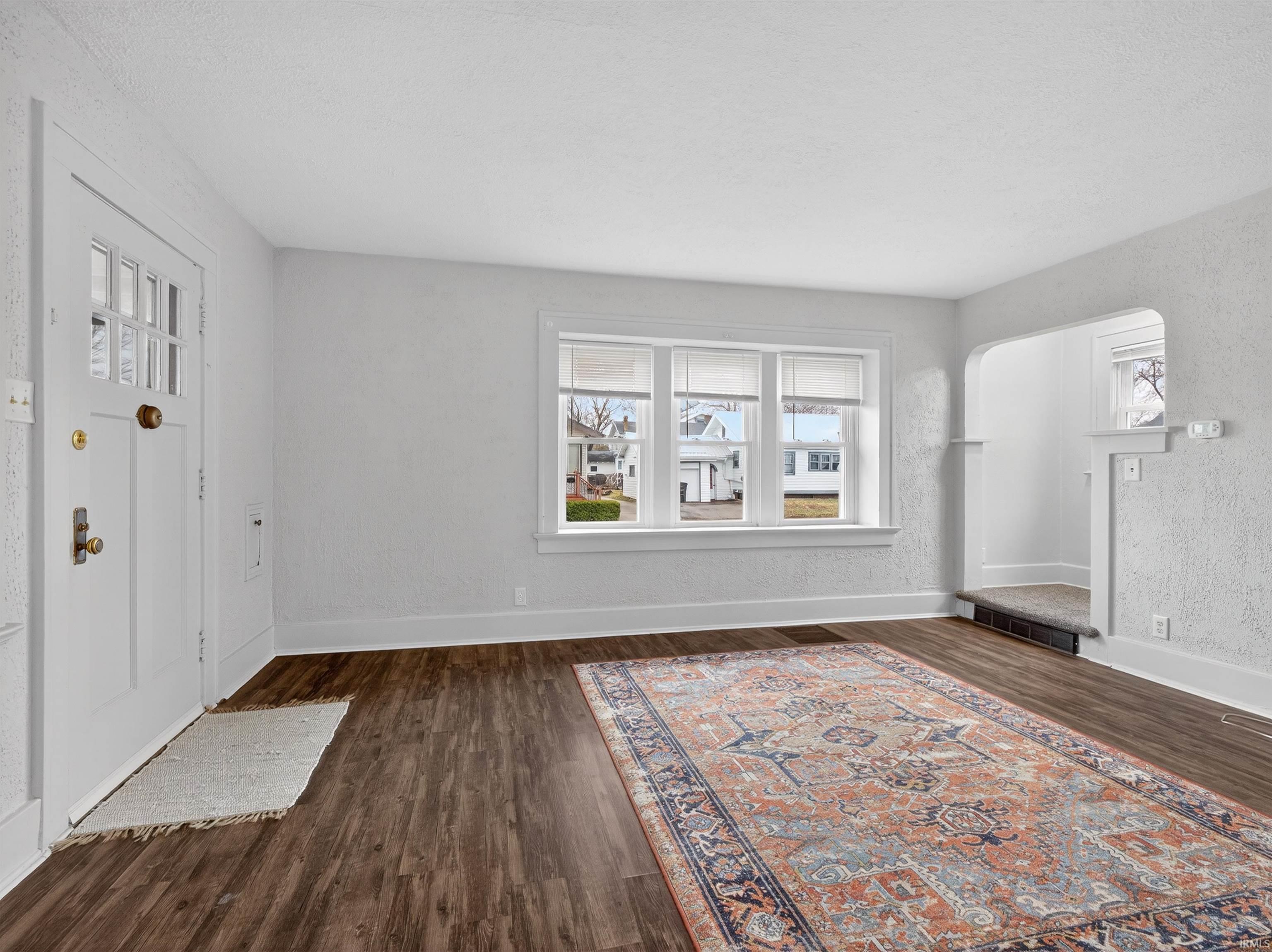 Foyer entrance with dark wood-style flooring and arched walkways