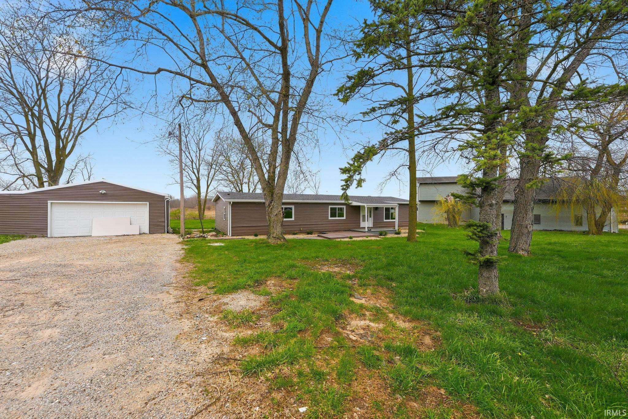 View of front of house featuring an outbuilding, a detached garage, a front lawn, and a patio area