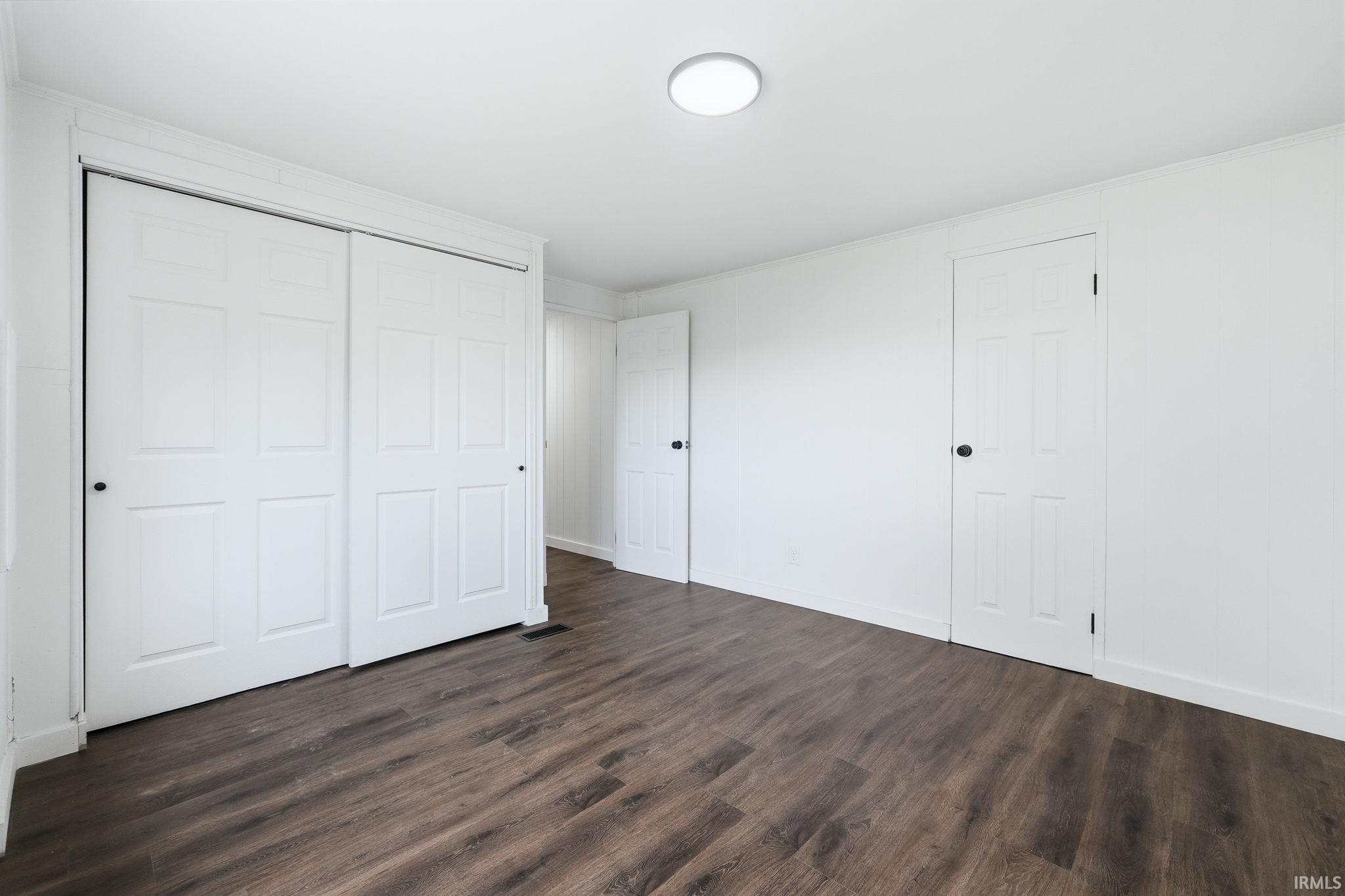 Unfurnished bedroom featuring dark wood-style floors and a closet