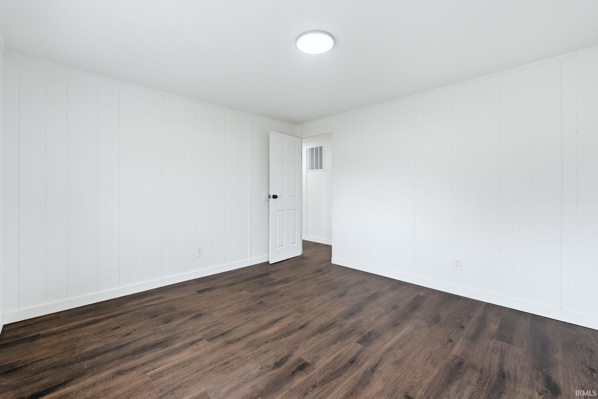 Spare room featuring dark wood-style floors and baseboards