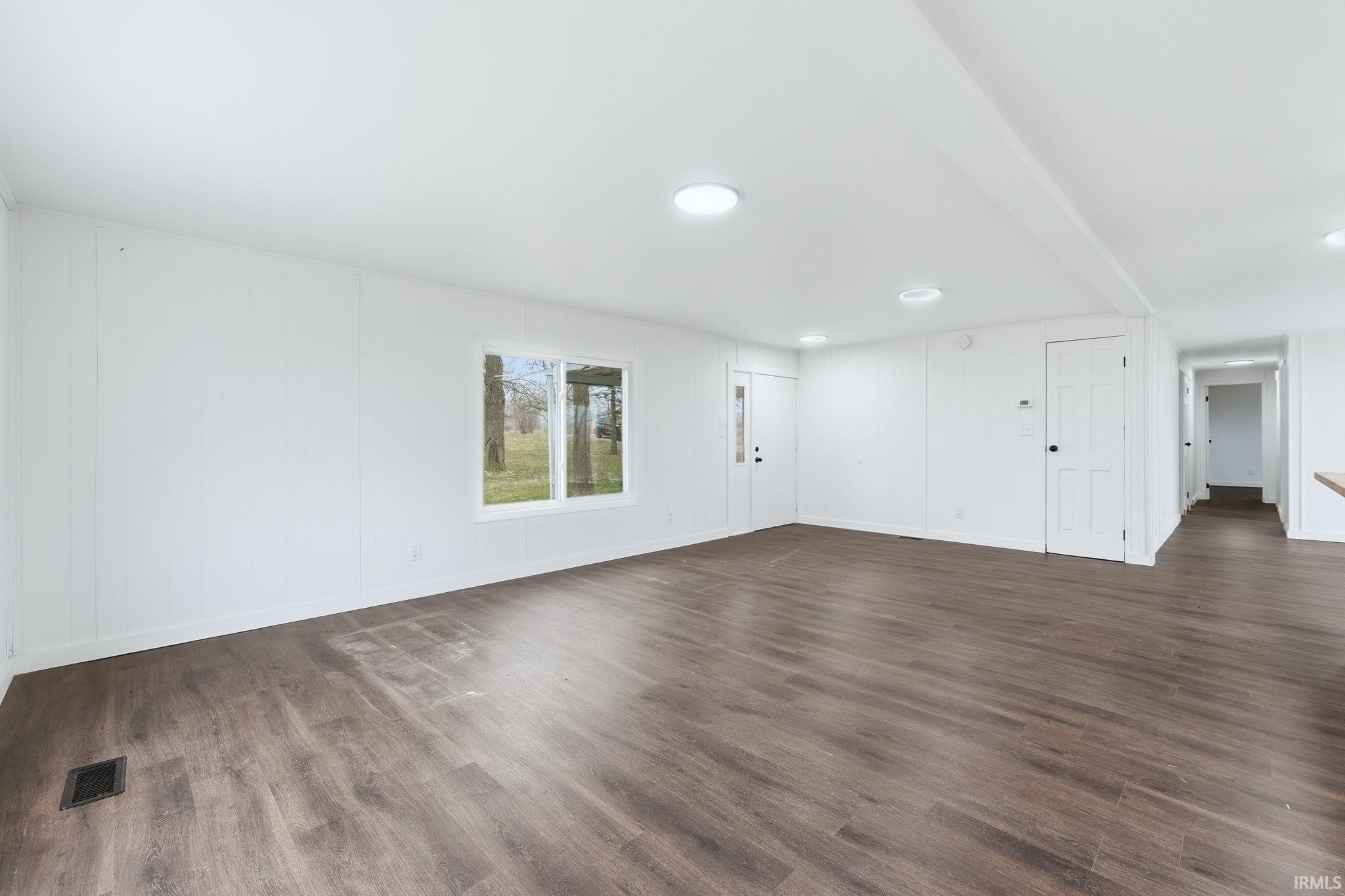 Empty room featuring dark wood-style floors and baseboards