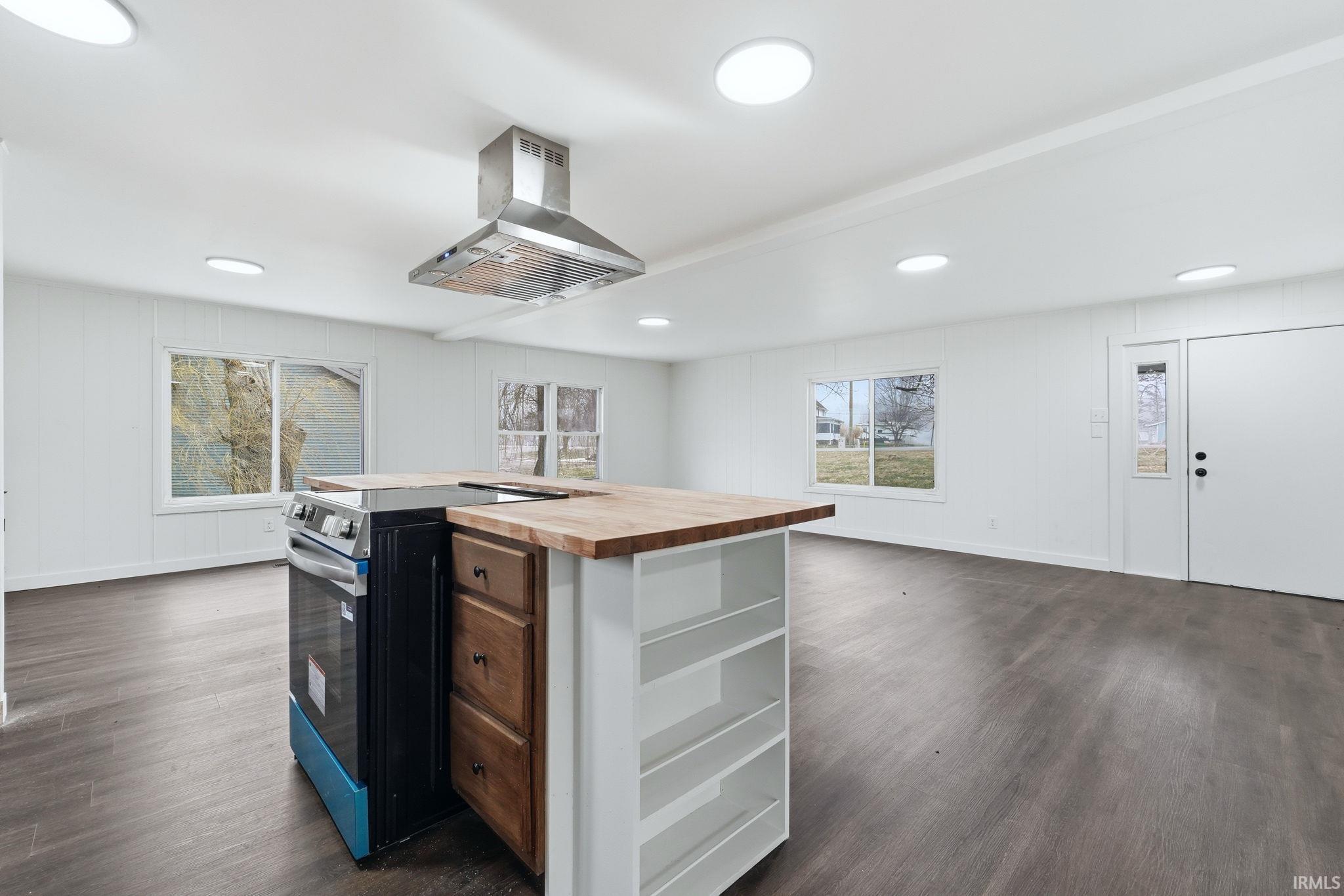 Kitchen featuring butcher block counters, stainless steel electric stove, island range hood, a kitchen island, and dark wood-type flooring